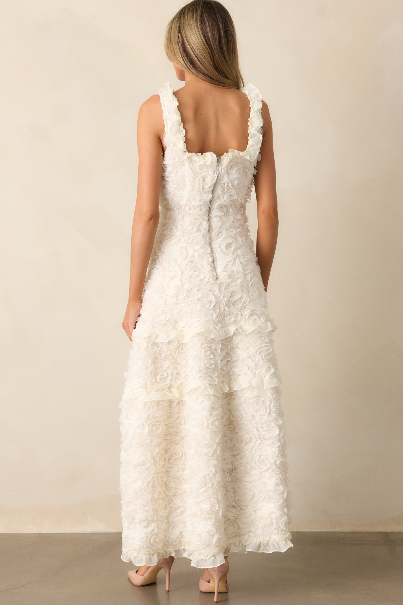 The back of the ivory dress, showcasing the silver back zipper and clean finish of the ruffle detailing on the shoulders and hem.