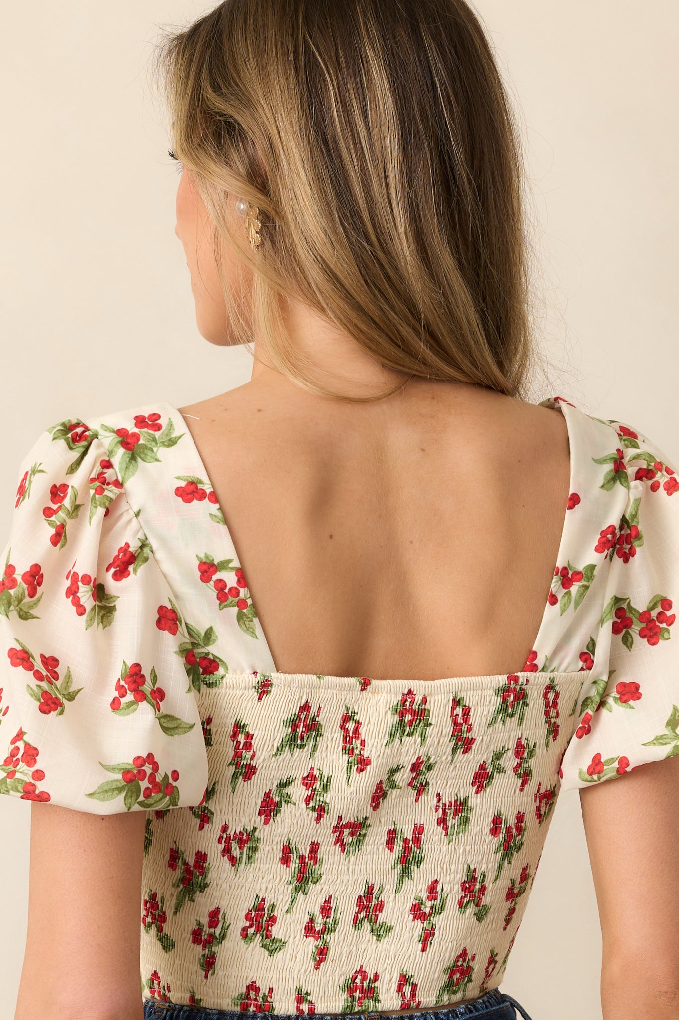 The back view highlights the fully smocked design, providing a fitted yet comfortable shape to this stylish ivory floral top.