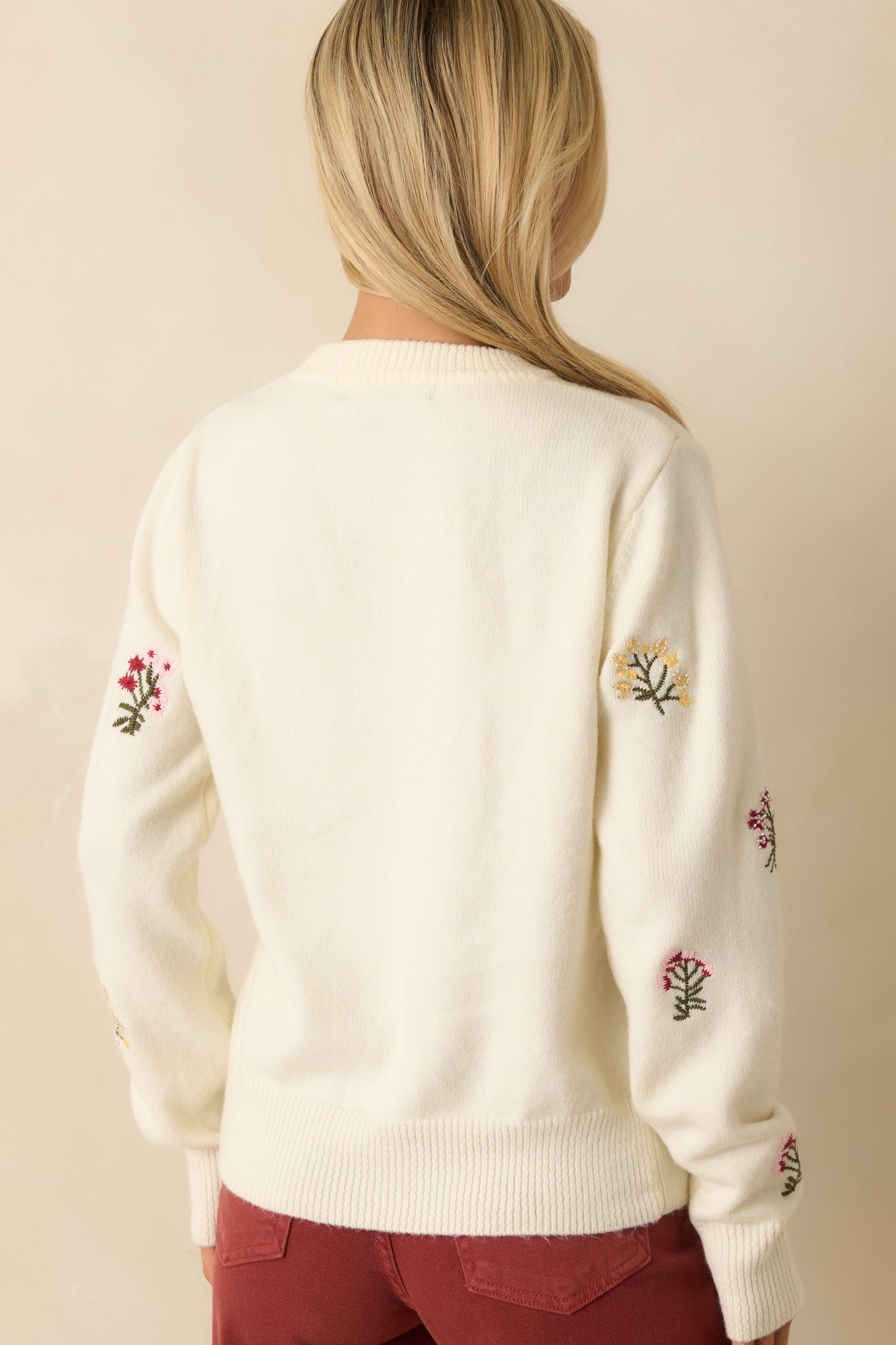 Back view showing the ivory knit fabric, relaxed fit, and ribbed hem along the back of the sweater.