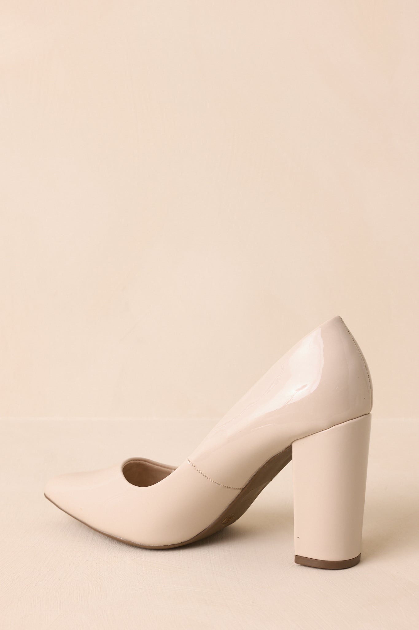 A back view of the ivory pumps highlighting the glossy patent heel and streamlined silhouette.