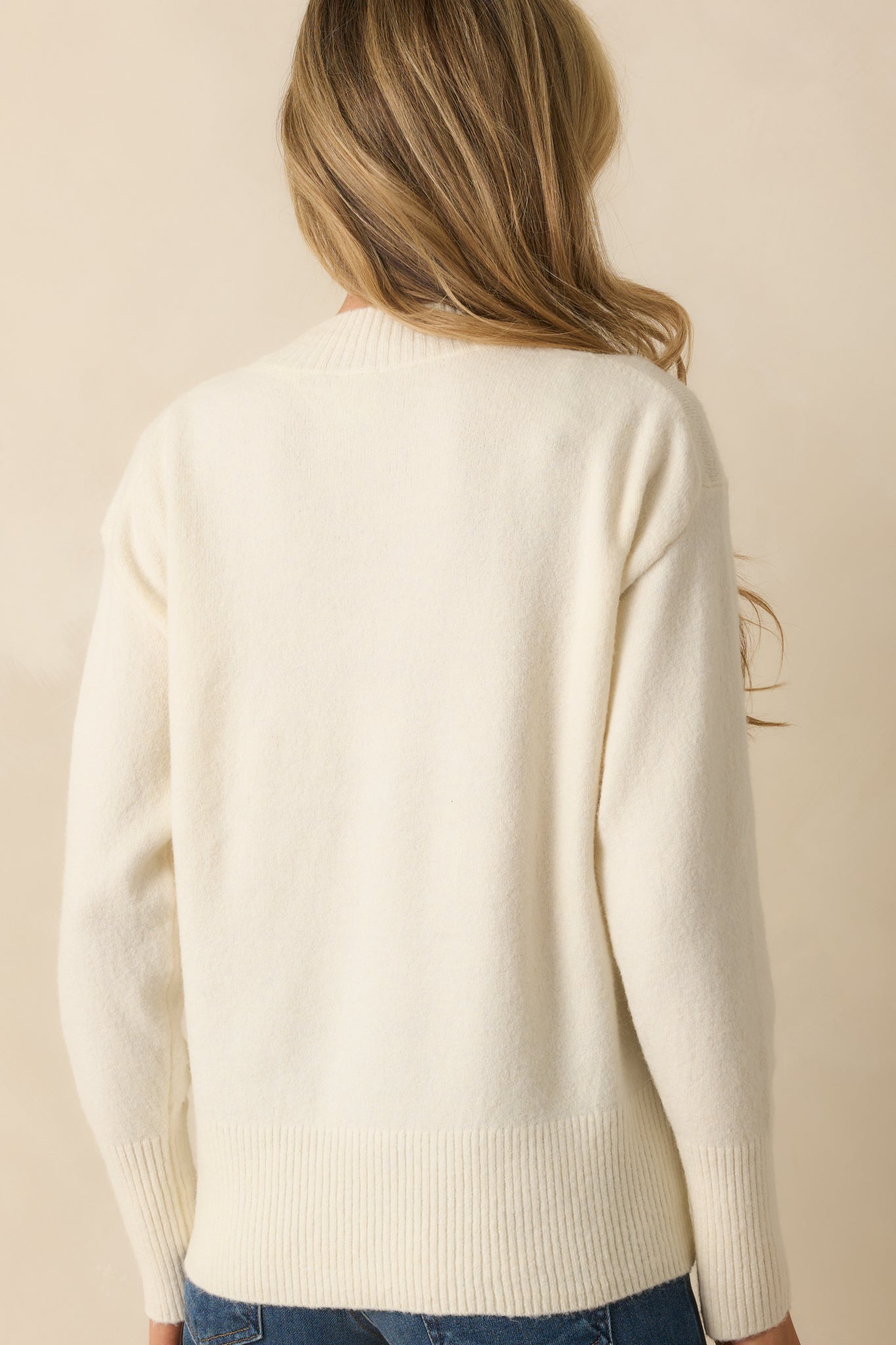 Rear view of the ivory soft knit sweater showing long sleeves, ribbed hem, and relaxed silhouette