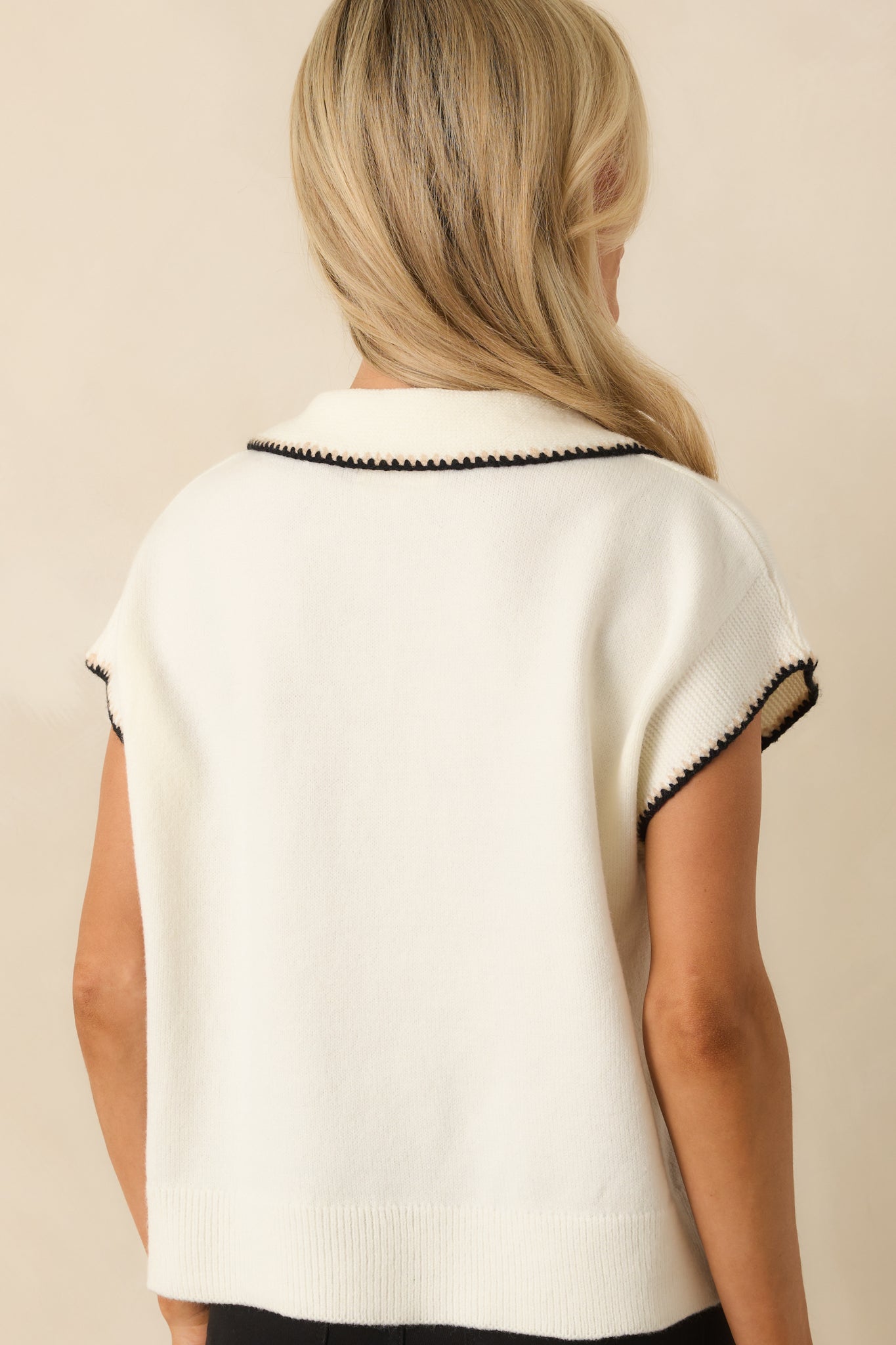 Rear view of ivory top displaying short cap sleeves, relaxed fit, and smooth knit fabric.