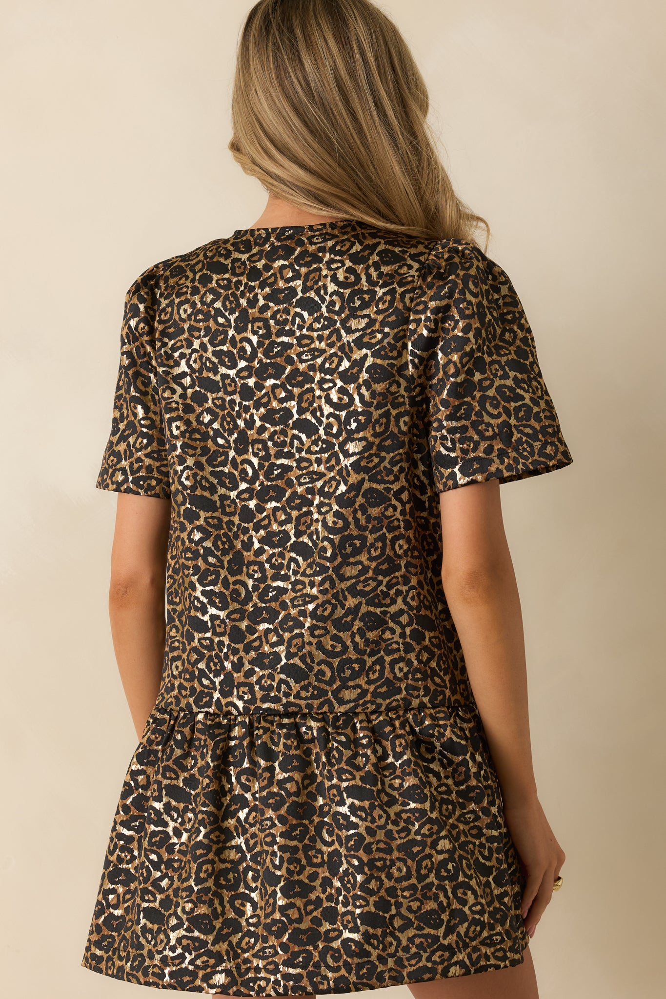 Rear view of the leopard print mini dress highlighting the smooth babydoll silhouette and layered skirt finish.