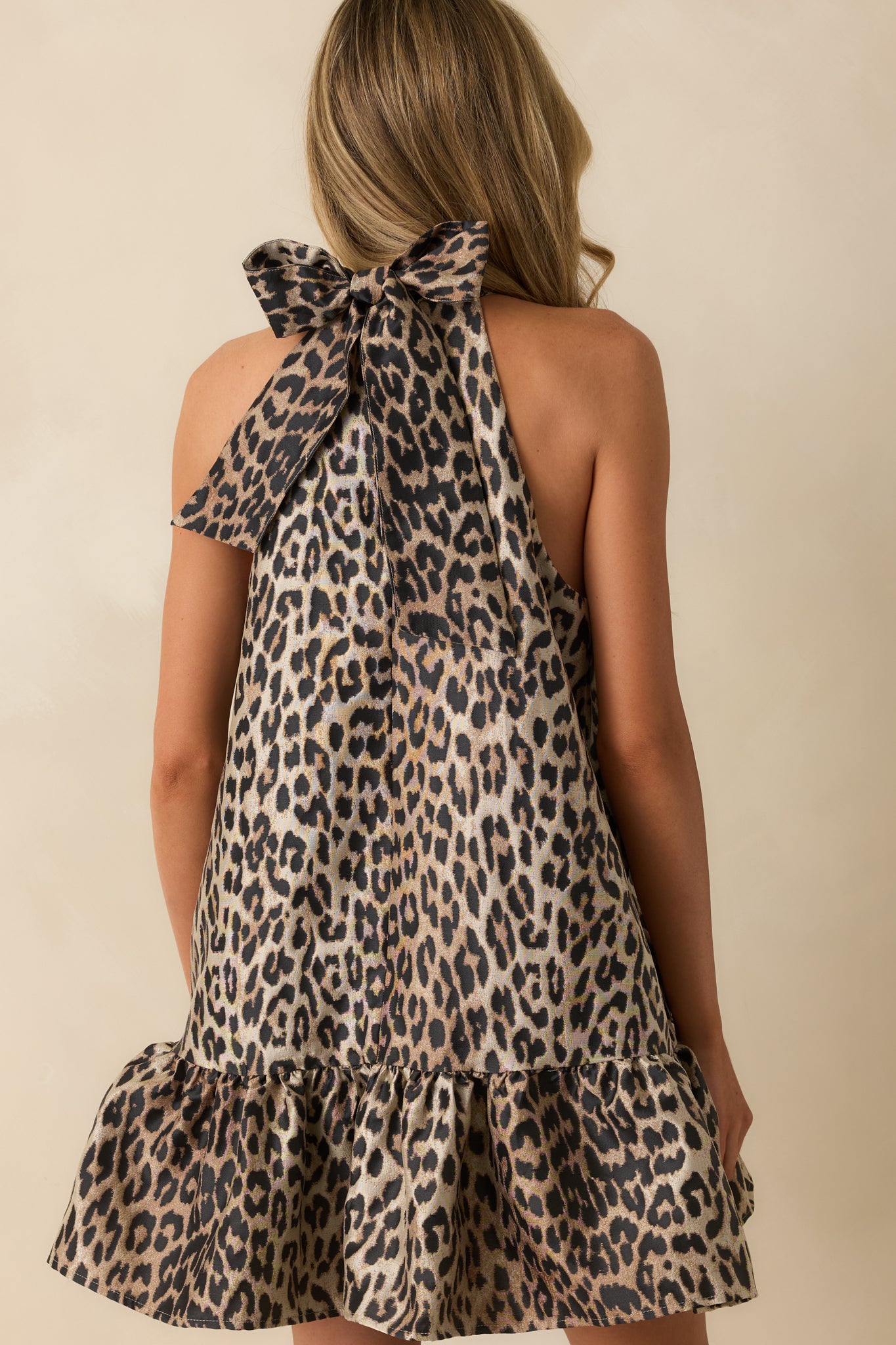Rear view of the leopard print mini dress featuring the self-tie bow halter and smooth, lined finish.