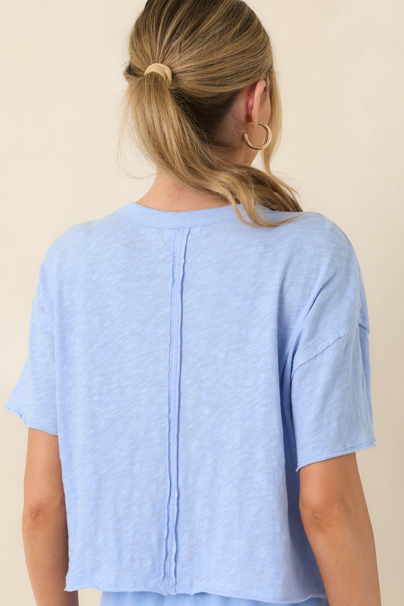 Back view of the light blue tee highlighting the exposed center back seam and relaxed silhouette.