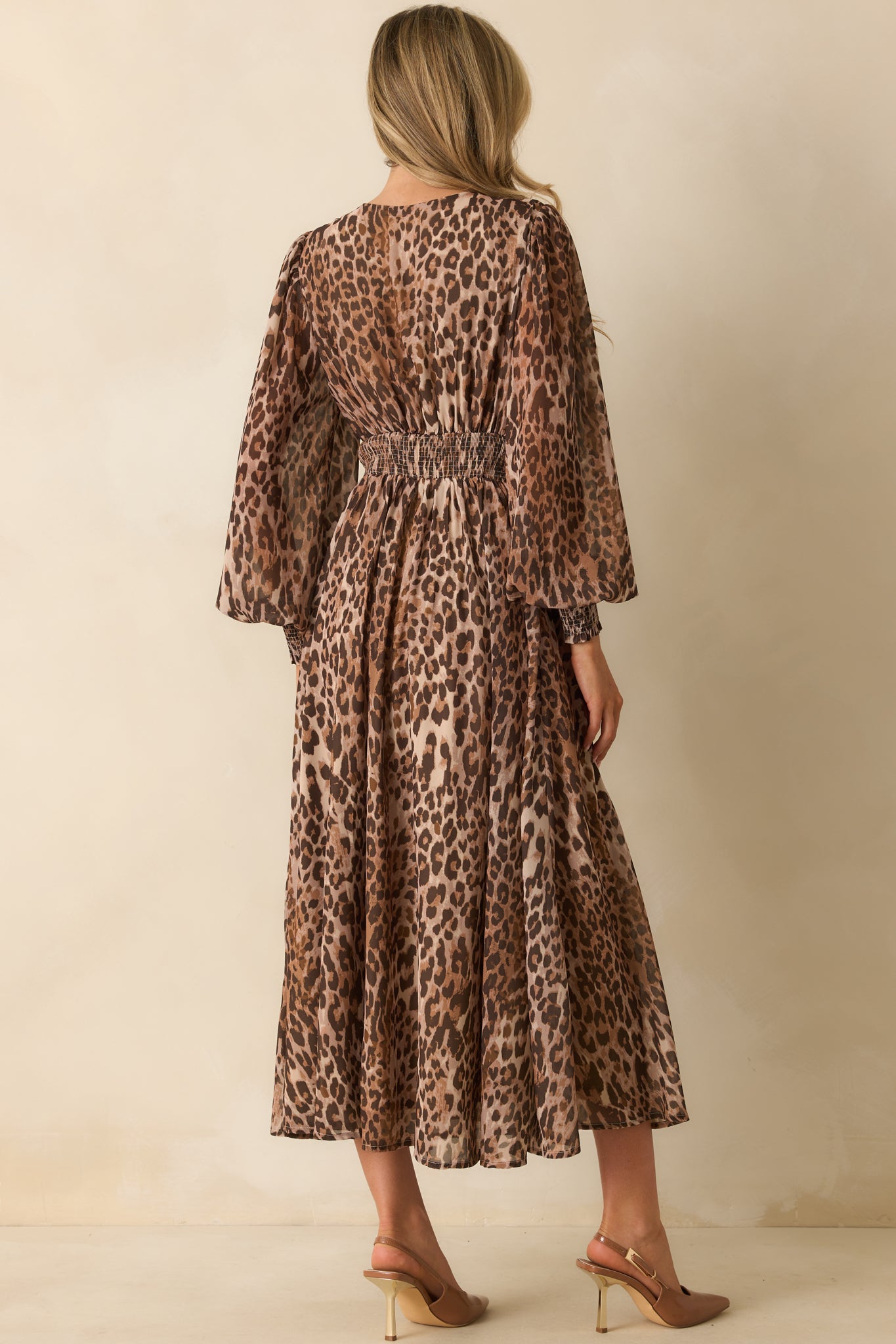 A back view of the maxi dress showing the elastic smocked insert, full-length lining, and flowing skirt with leopard print.