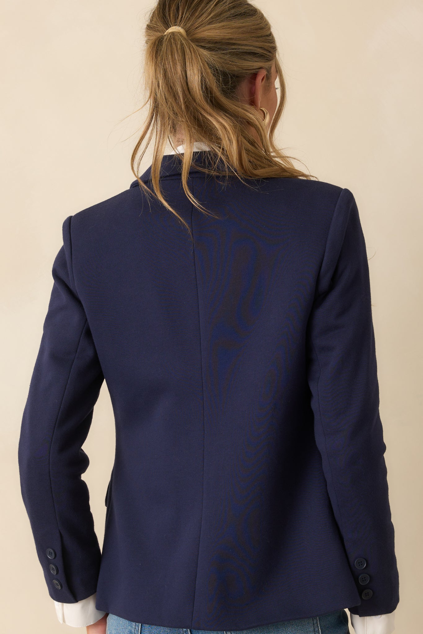 A back view of the navy blazer displaying the structured shoulders and tailored seams.