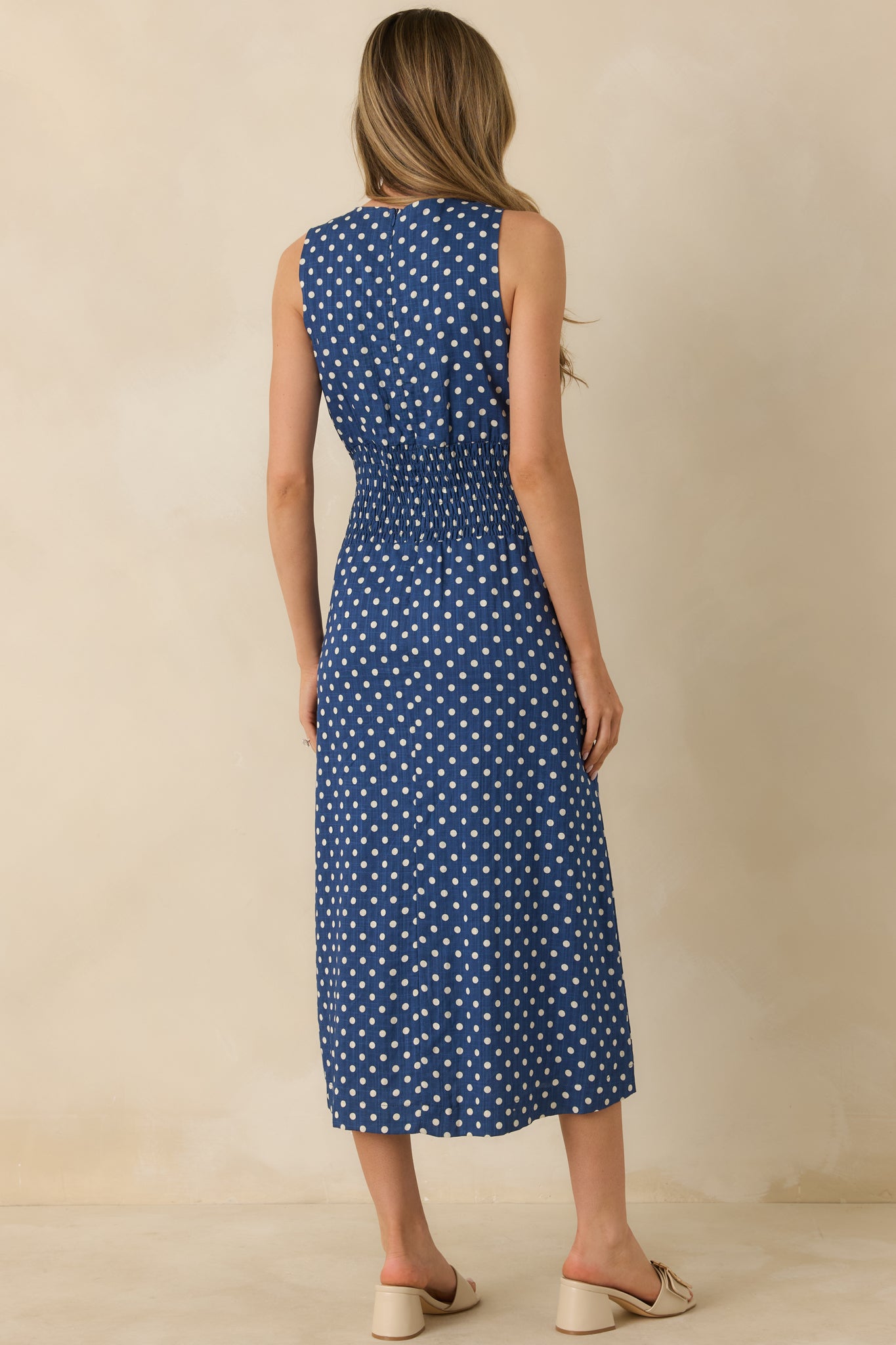 Back view of the navy dress featuring its sleeveless design and midi-length.