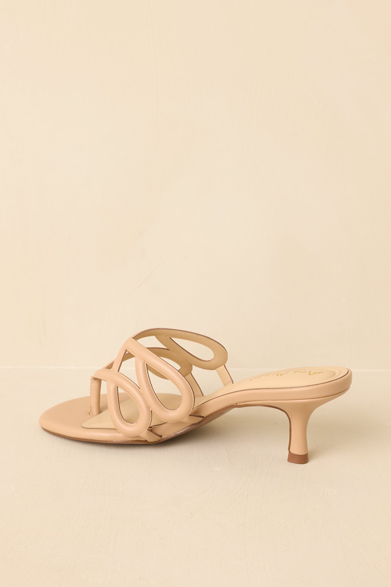 Back view of beige sandals showing heel shape and open back design.