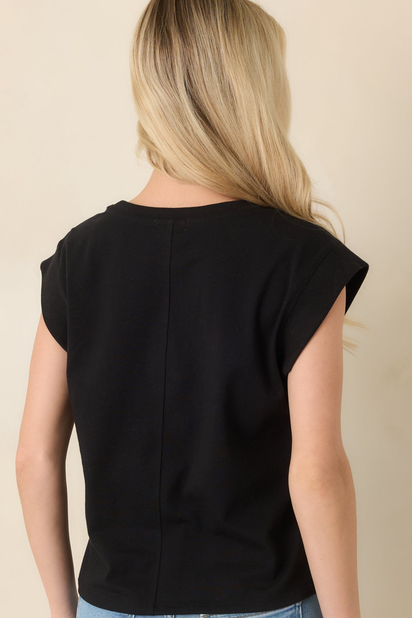 Back view of black cotton jersey tee showcasing relaxed fit and cap sleeve silhouette.