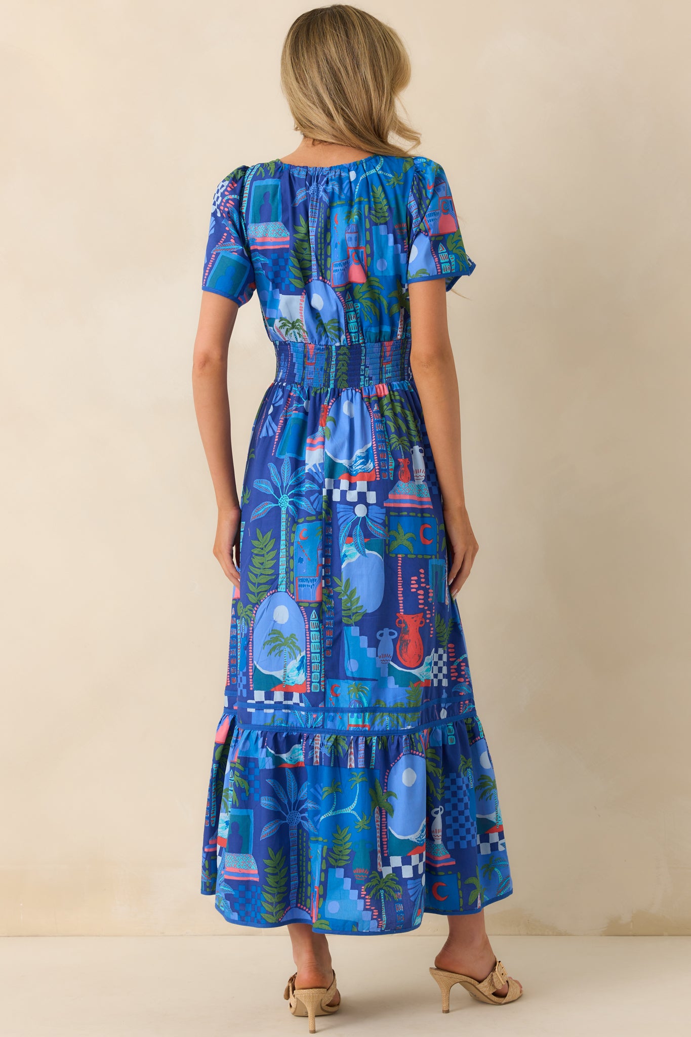 Back view of the dress displaying the continuation of the abstract print, smocked waist from behind, and the tiered skirt design.