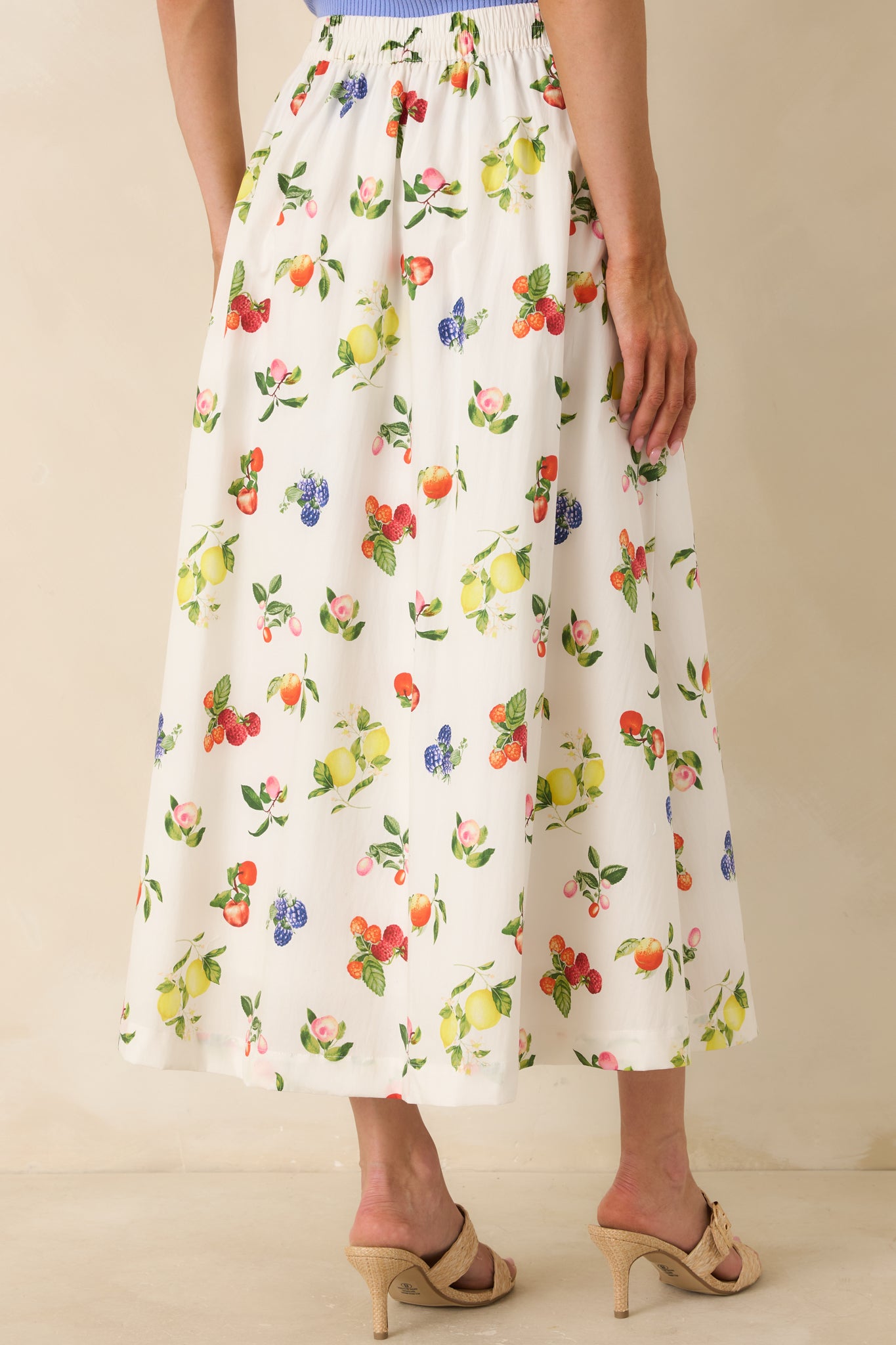 Back view of midi skirt featuring elastic waistband, functional pockets, and allover fruit print