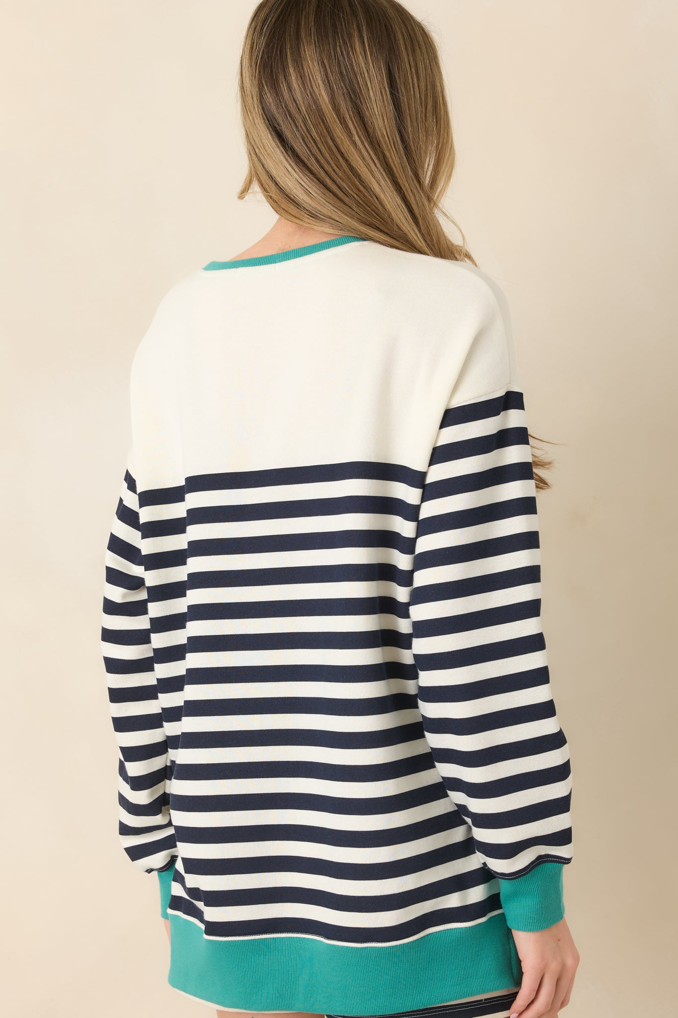 Back view of navy and ivory striped sweatshirt featuring a relaxed silhouette, long sleeves, and contrasting ribbed hem.