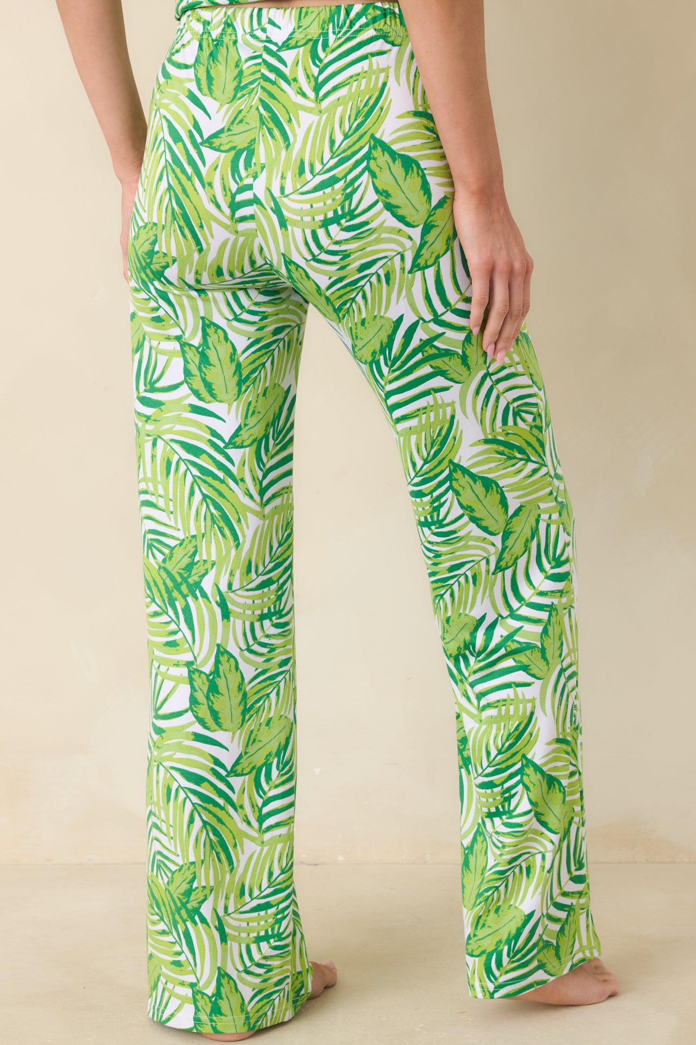 Back view of green palm-print pants showing relaxed silhouette, elastic waistband, and smooth leg drape