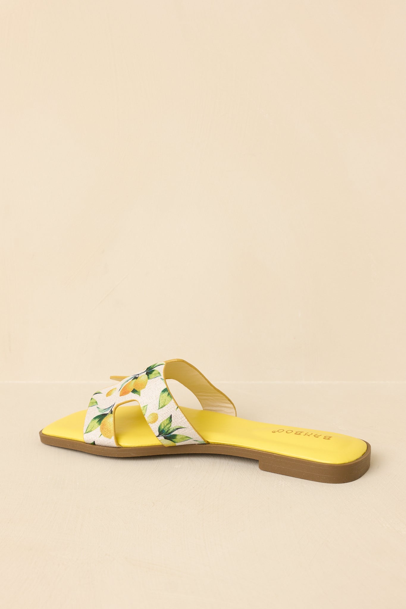 Back view of slide sandals featuring flat sole, smooth faux leather base, and minimal heel detail