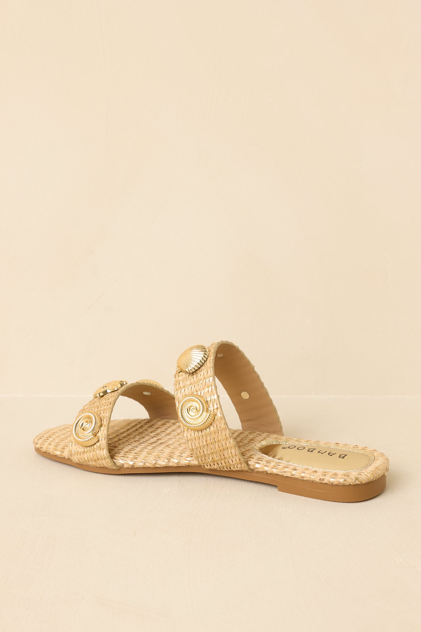 Back view of gold raffia slip-on sandals showcasing the flat sole and woven strap construction.