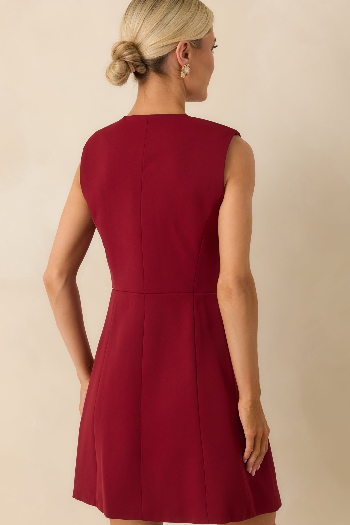 Back view of the burgundy mini dress displaying the sleeveless cut and smooth, unembellished rear tailoring.