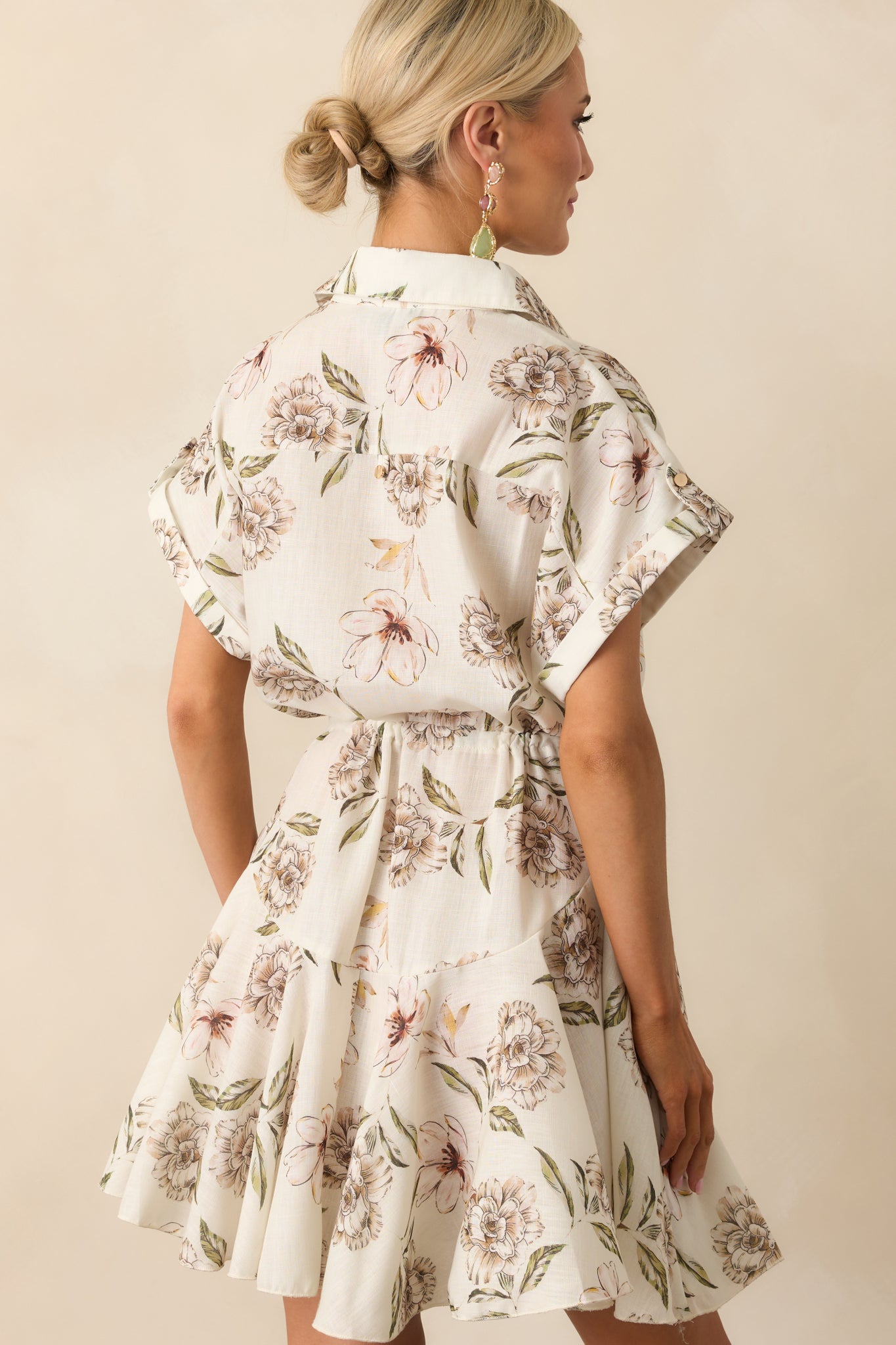 Back view of the dress showing the continuation of the green floral print, cuffed sleeves, and relaxed fit of the swing skirt from behind.