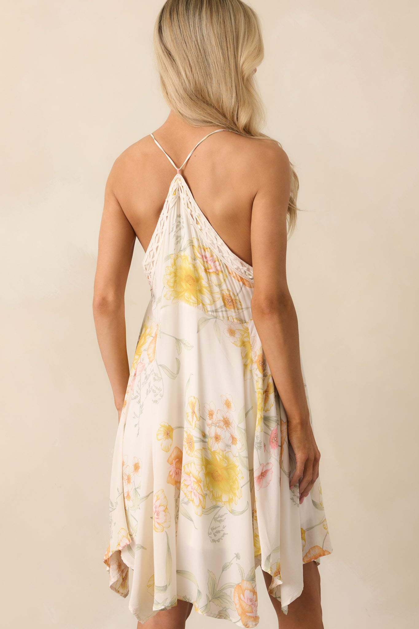 Back view of the mini dress displaying the open racerback design and full ivory lining beneath the floral print.