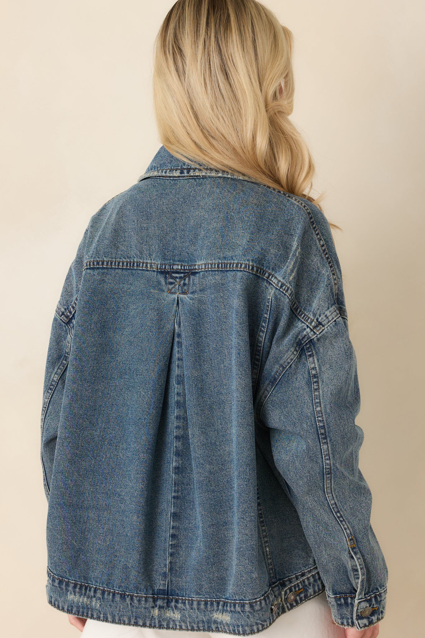 Back view of the medium wash denim jacket featuring a relaxed fit and clean seam detailing.