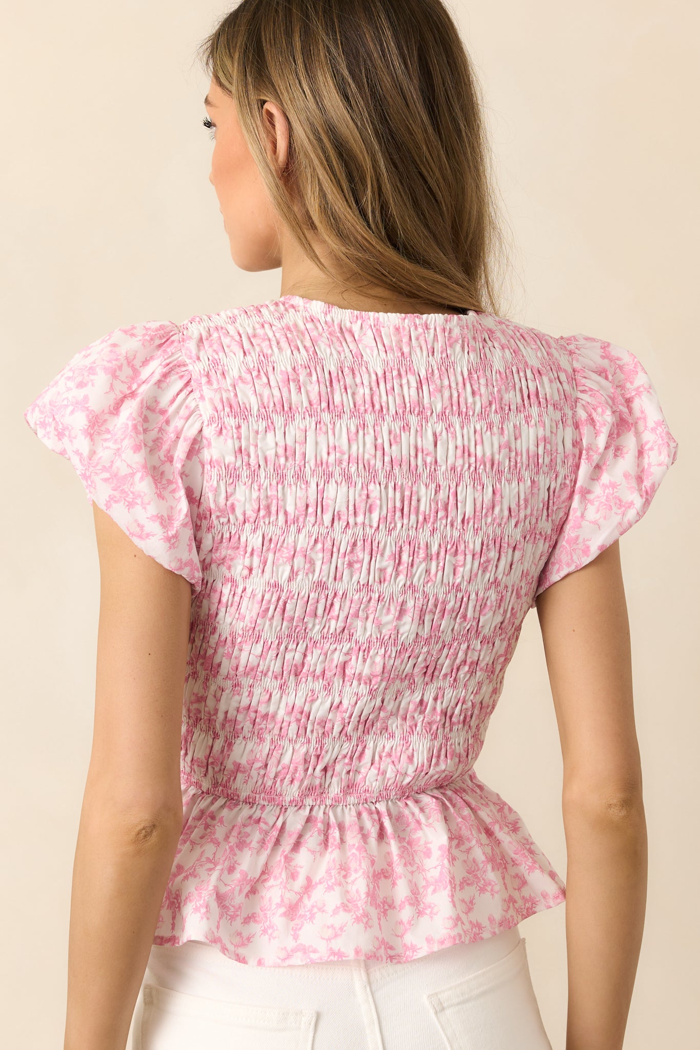 The back view of this pink top highlights its lightweight flutter sleeves and flowy peplum hem for an airy, effortless finish.