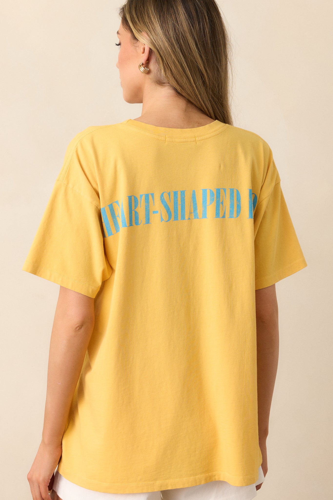 The back of this yellow tee features the track's name stamped in simple, clean text, maintaining a minimalist style.