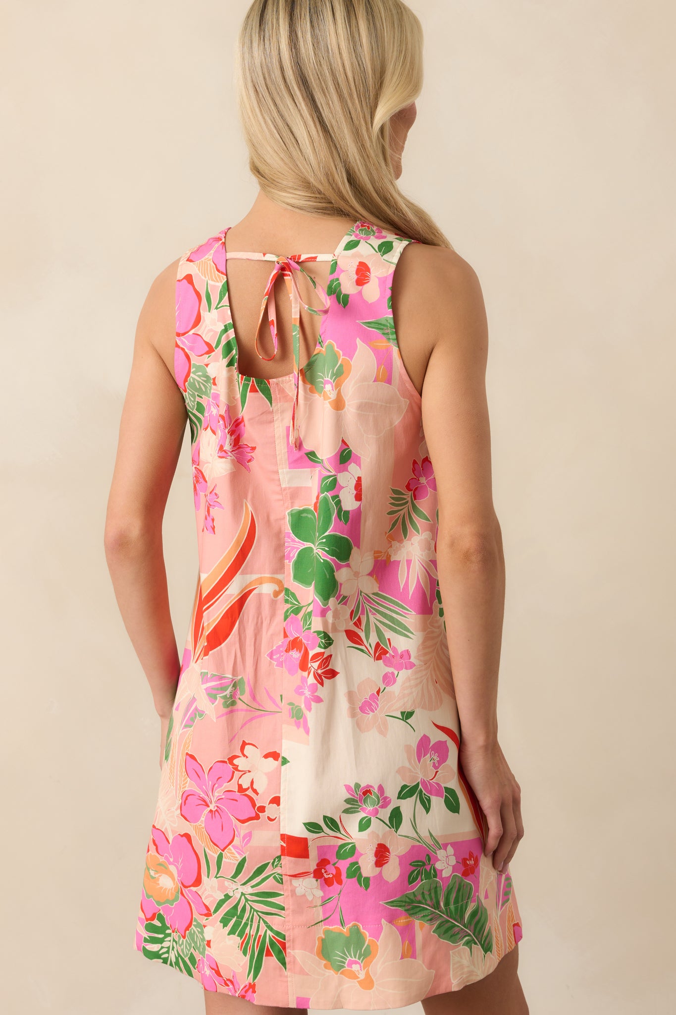 A view from behind of the pink mini dress featuring a scoop back, adjustable self-tie, and subtle pocket outline.