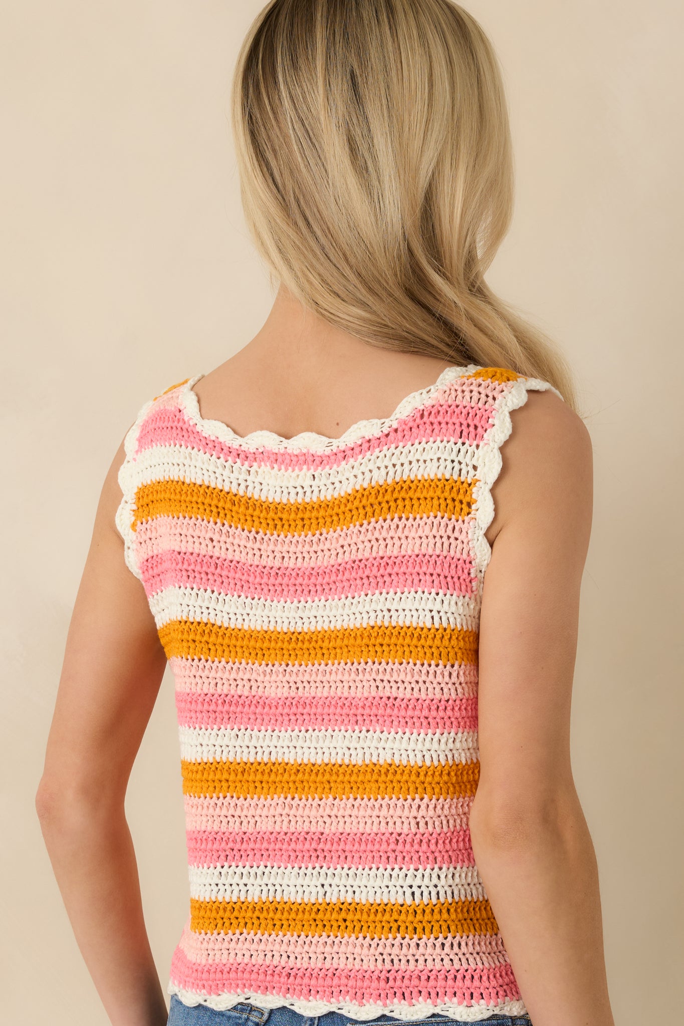 Back view of the pink and orange crochet tank displaying scalloped trim along the hem and arm openings and breathable open-knit fabric.