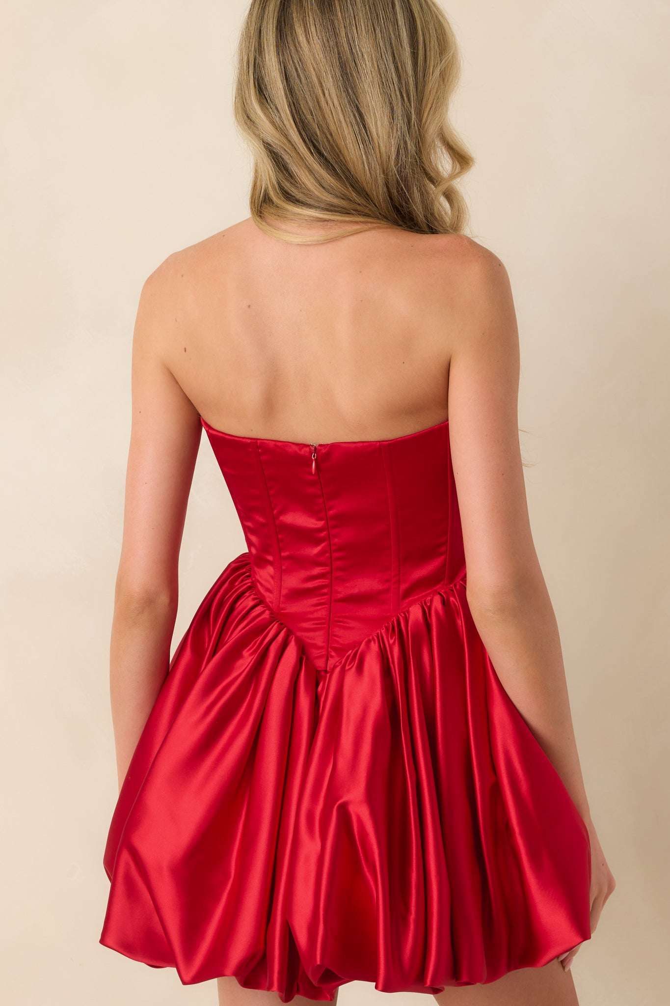 A back view of the red strapless mini dress showing the discrete back zipper and bubble skirt.