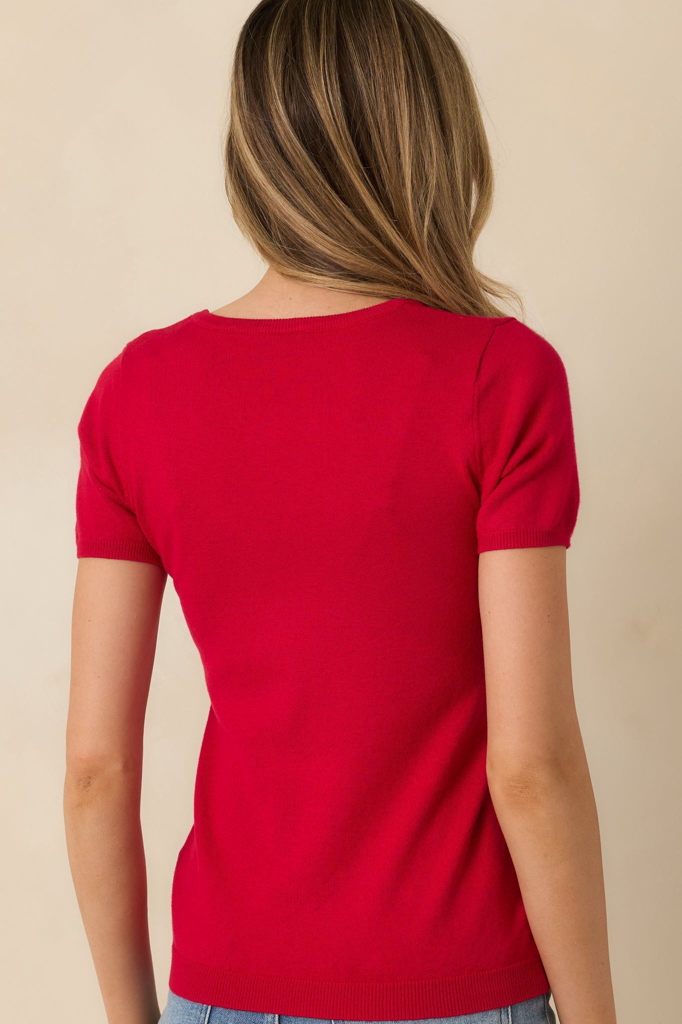 Back view of red sweater top showing smooth knit fabric and short sleeves.