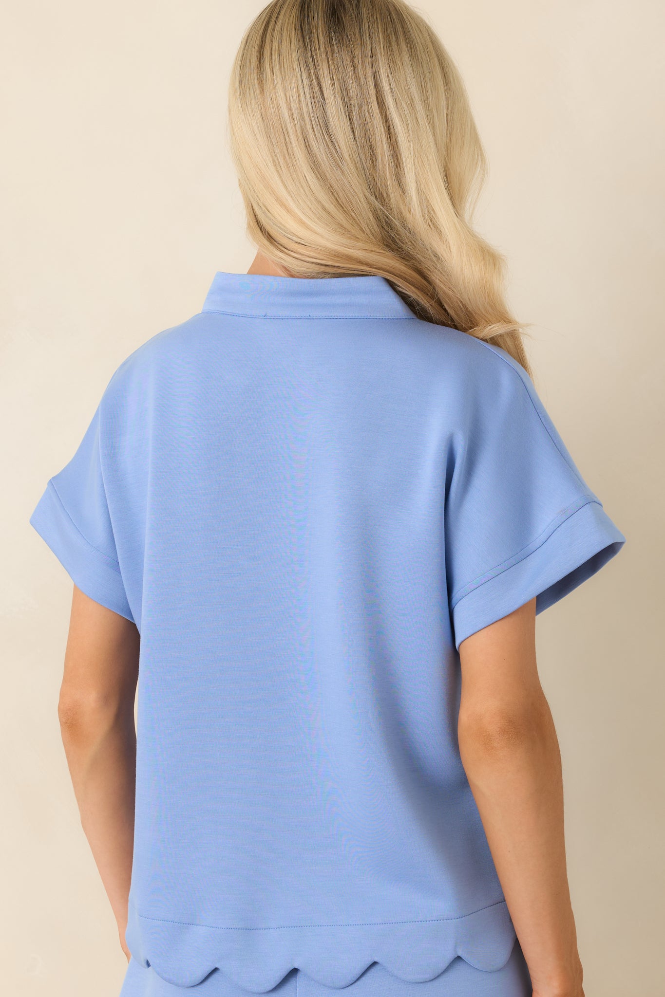 Back view of the relaxed-fit top showcasing the easy silhouette, side slit design, and scalloped hem detail.