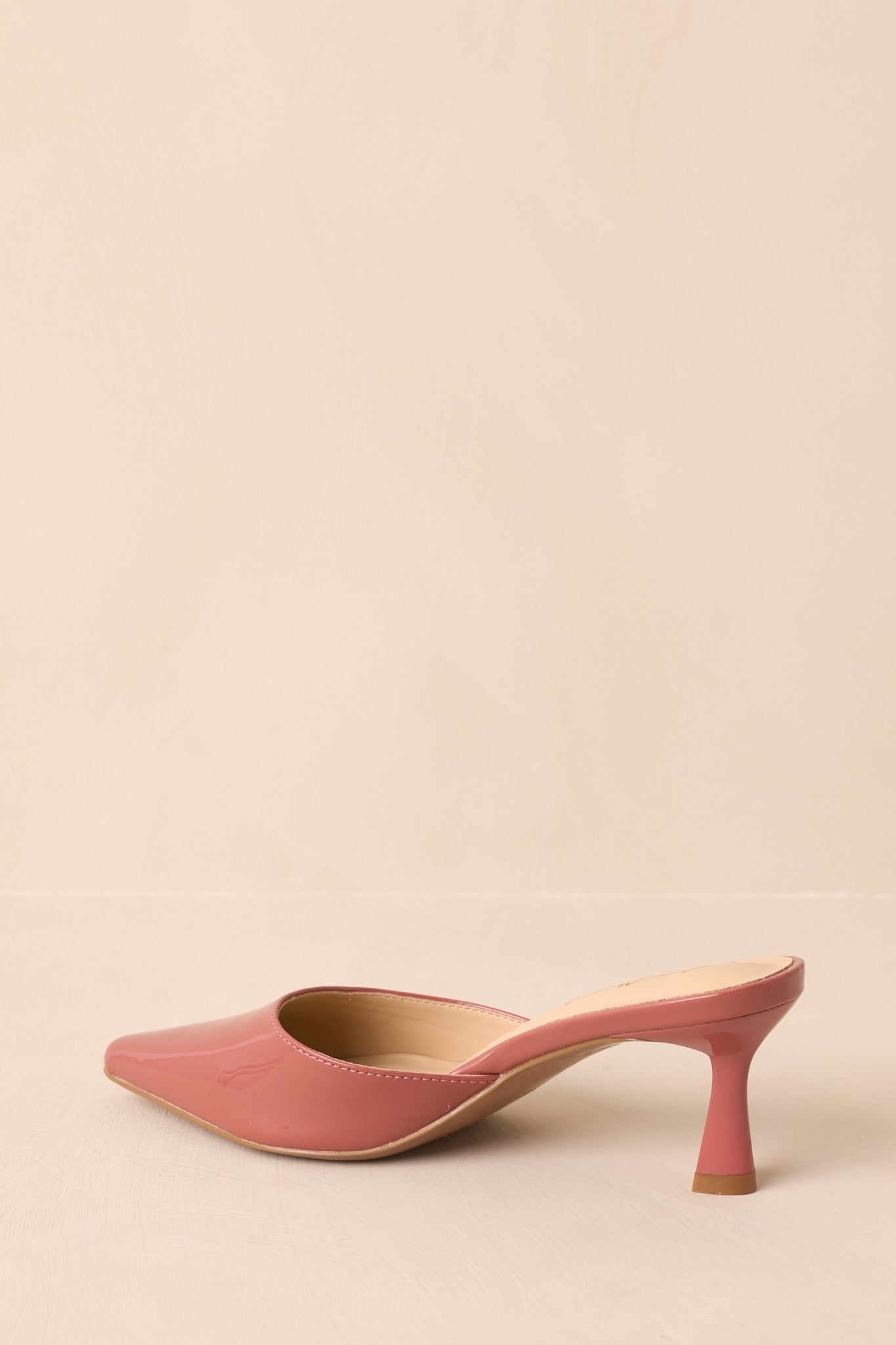 A back view of the rose pink mules highlighting the stiletto kitten heel and glossy finish.