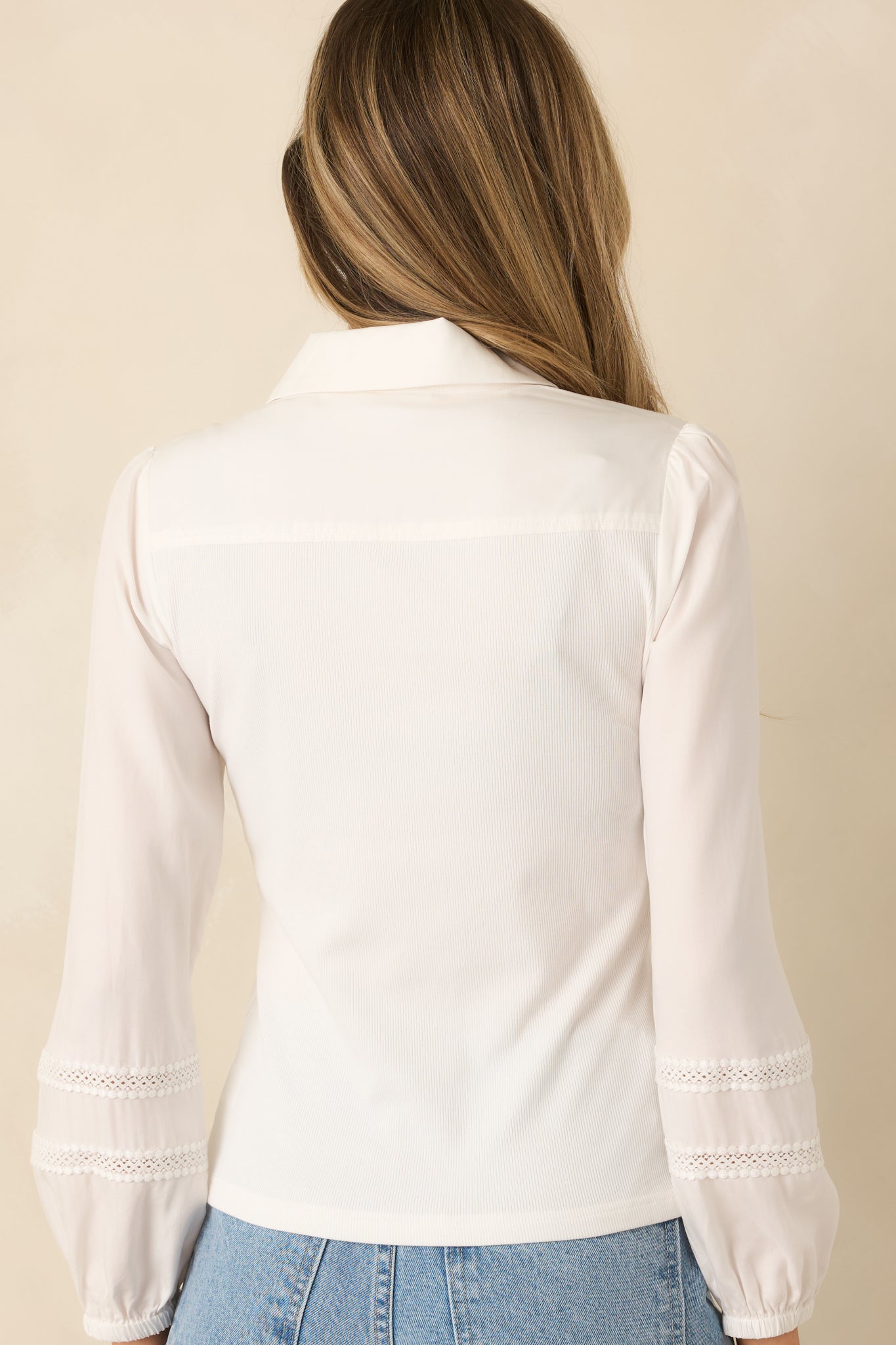 Back view of white ribbed knit top with long sleeves and smooth fitted silhouette, showing lace shoulder accents.