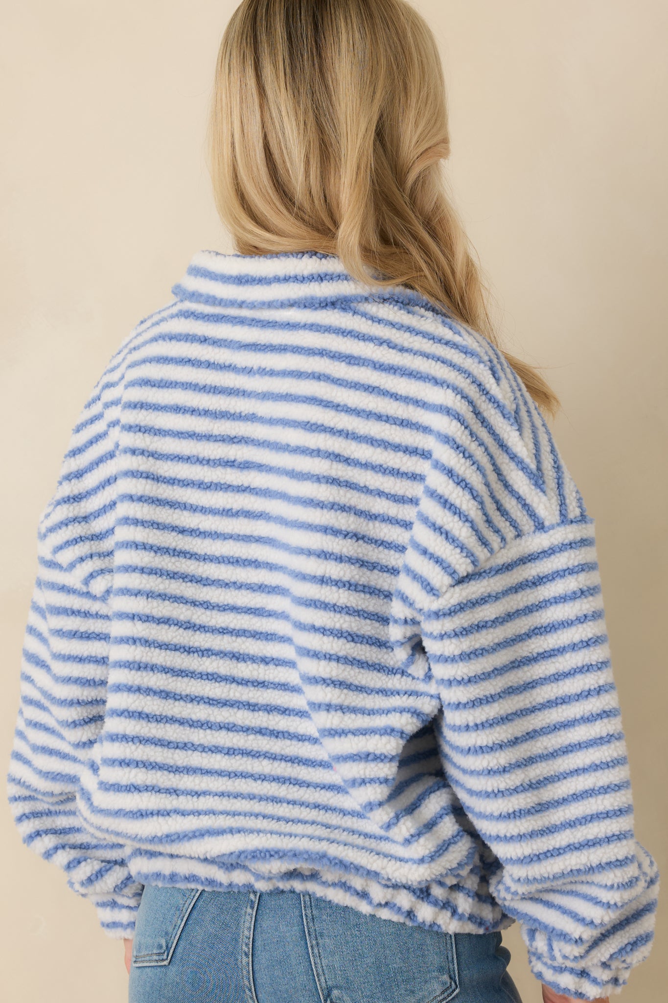 Back view of blue stripe bouclé pullover with relaxed fit and straight hem, showing soft textured knit fabric.