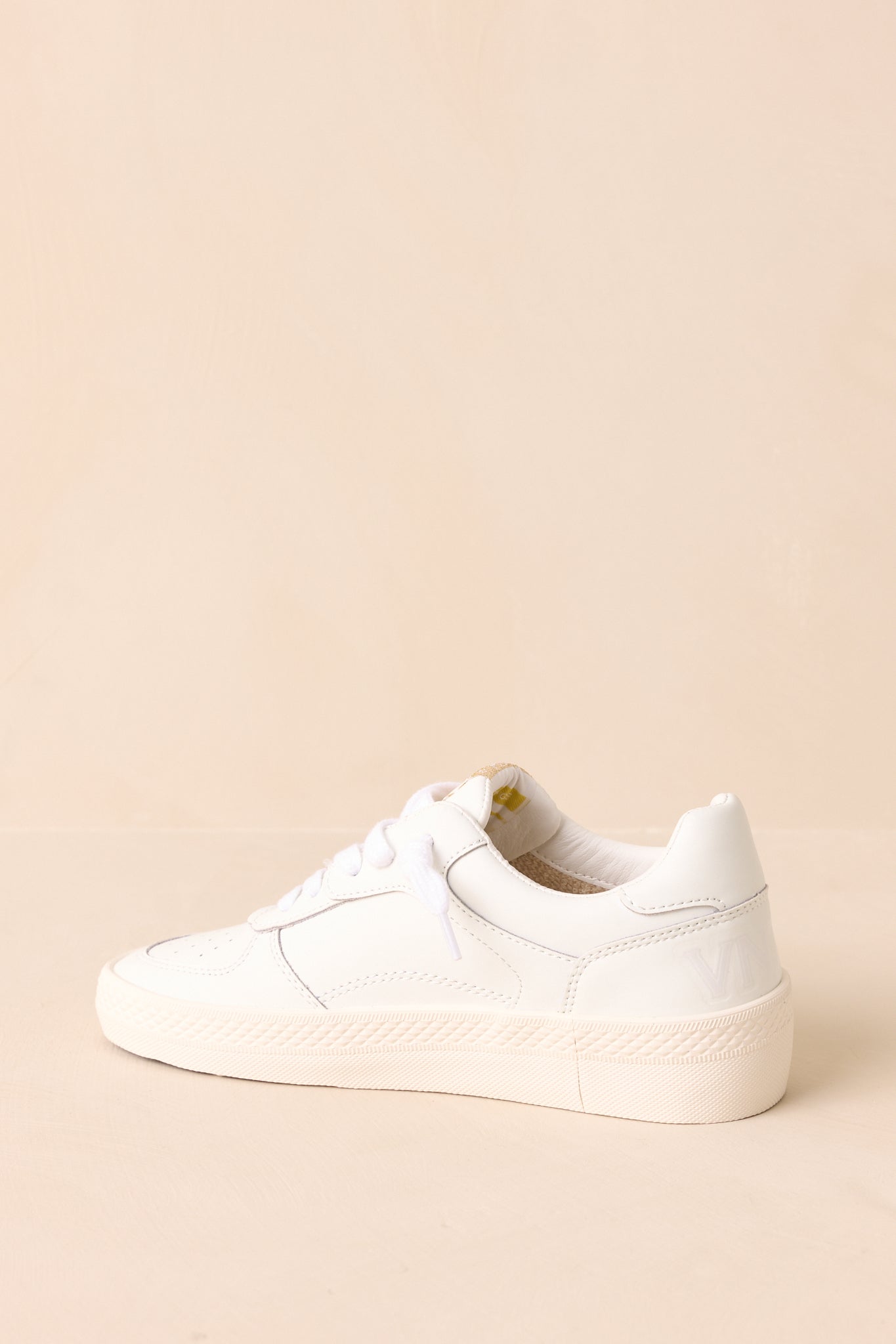 Back view of white sneakers showing the rubber platform sole and heel tab.