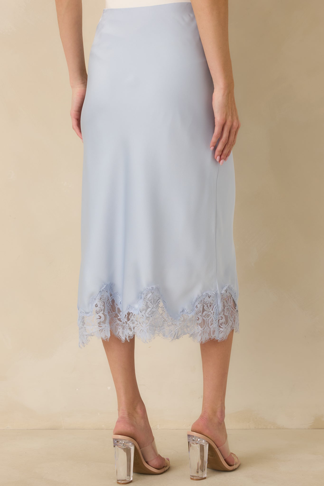 Back view of the blue satin midi skirt showing straight silhouette and smooth elastic waistband.