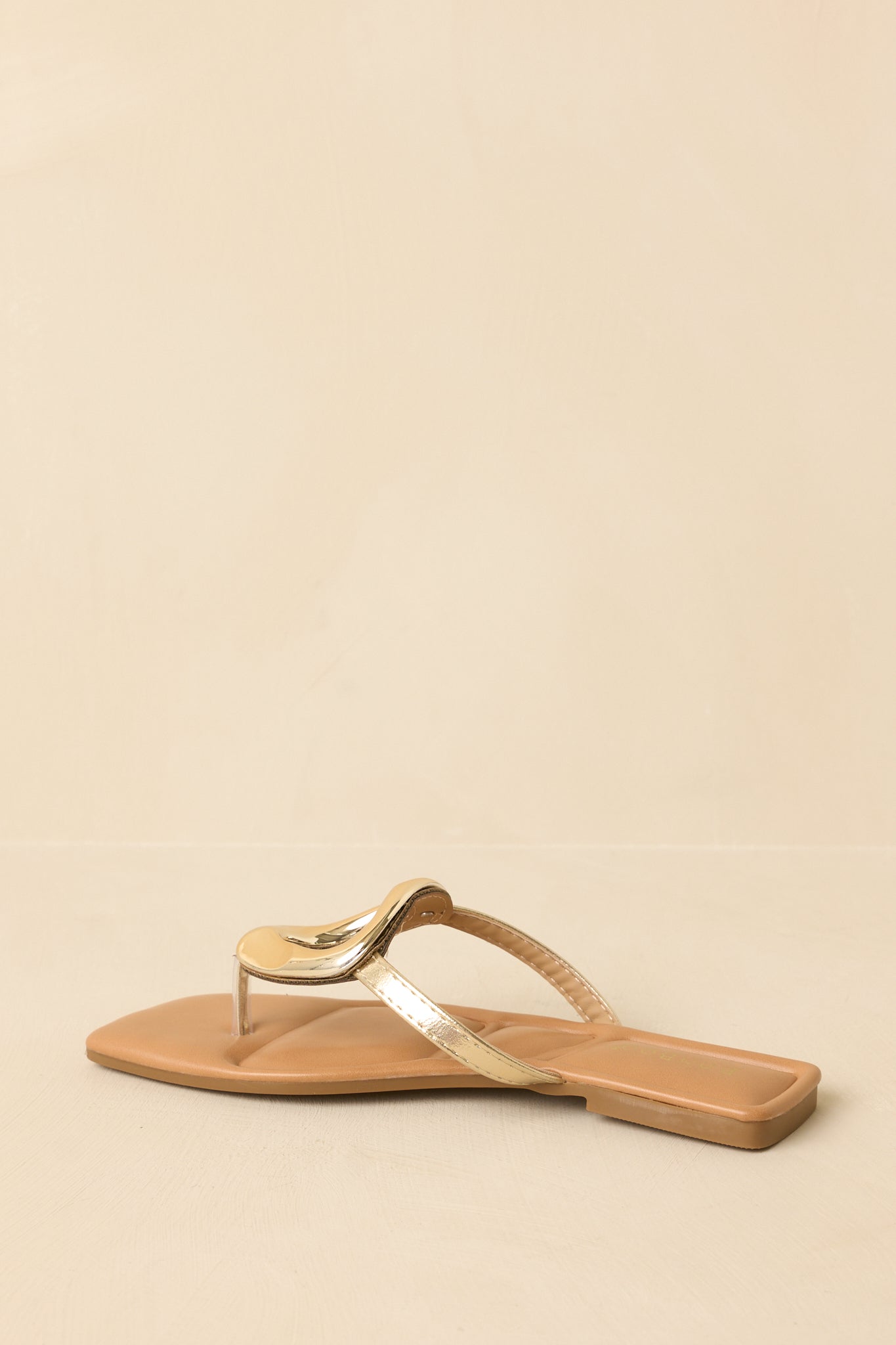 Back view of the gold flat thong sandals showing the smooth heel area and cushioned sole construction.