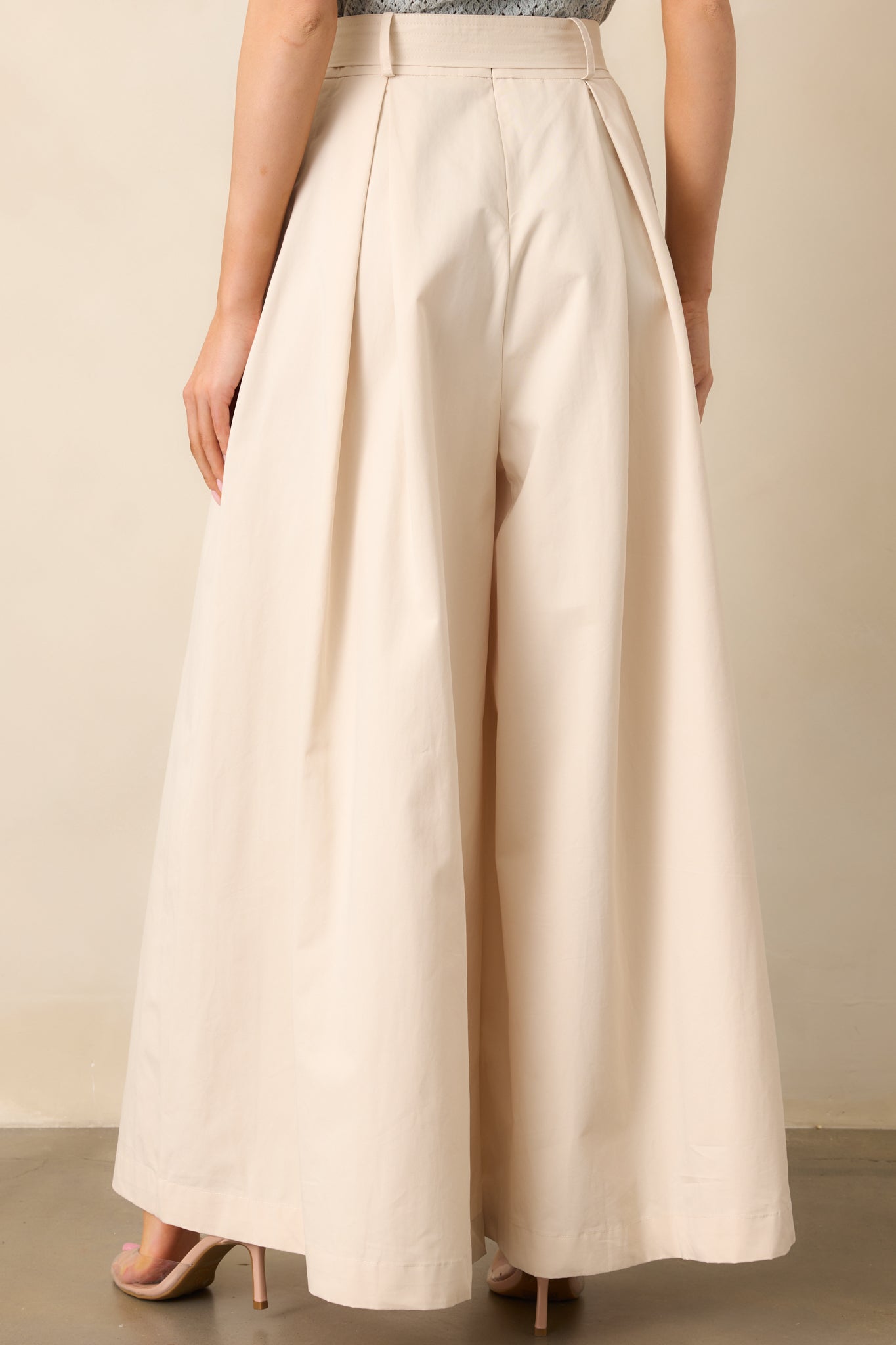 A complete back view of the ecru pants, showing the high-waisted fit and fluid wide-leg shape from behind.
