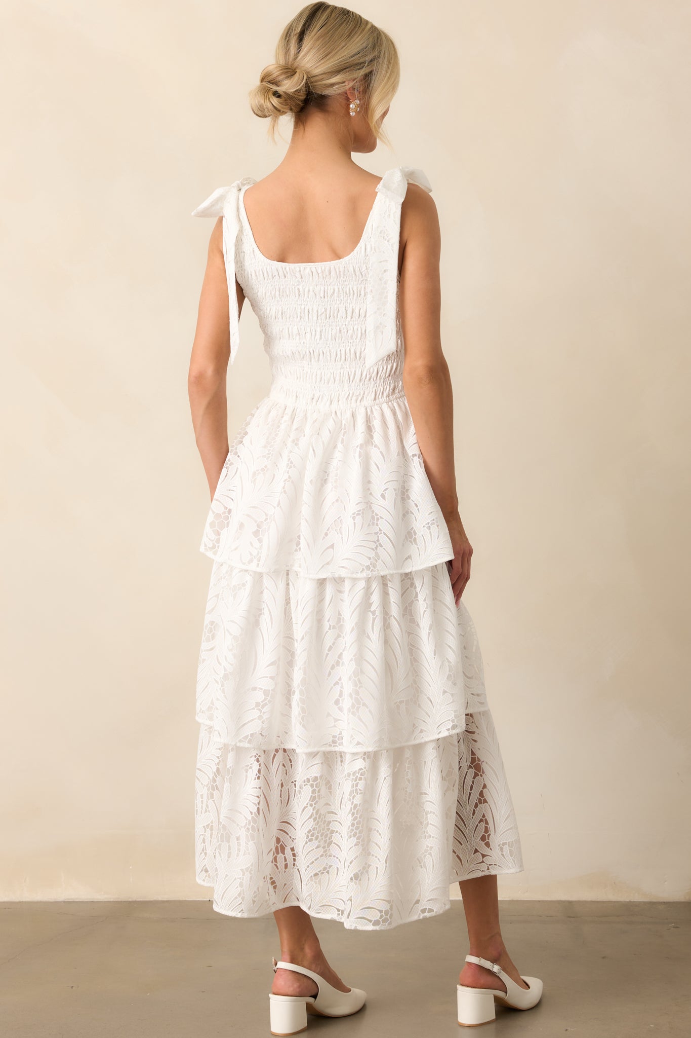 Ivory maxi dress from behind, featuring a smocked back, lace shoulder bows, and a tiered lace skirt with an ivory lining.