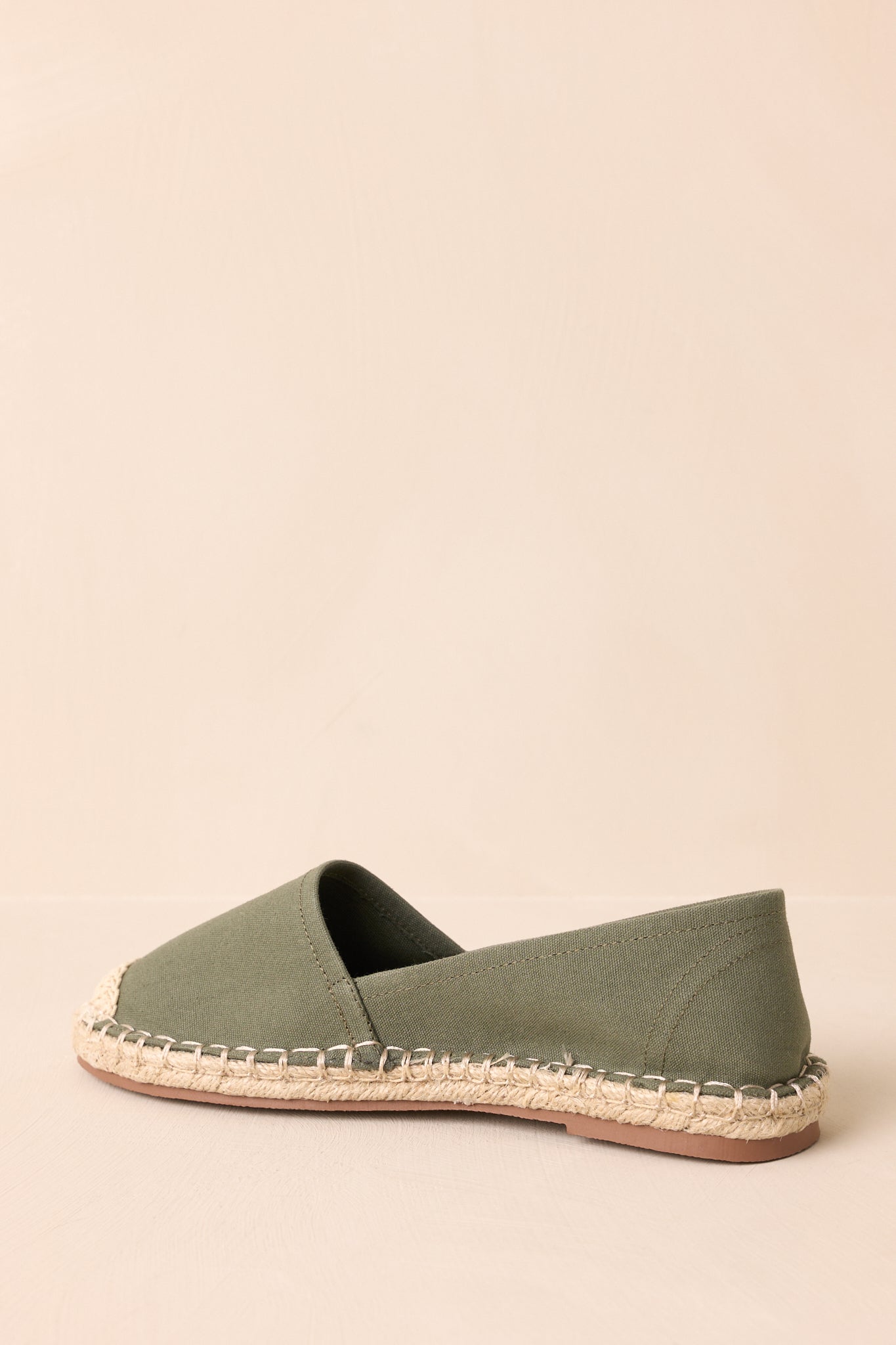 A back view of the earthy green flat shoes showing the rounded heel and jute-wrapped sole continuing to the back.