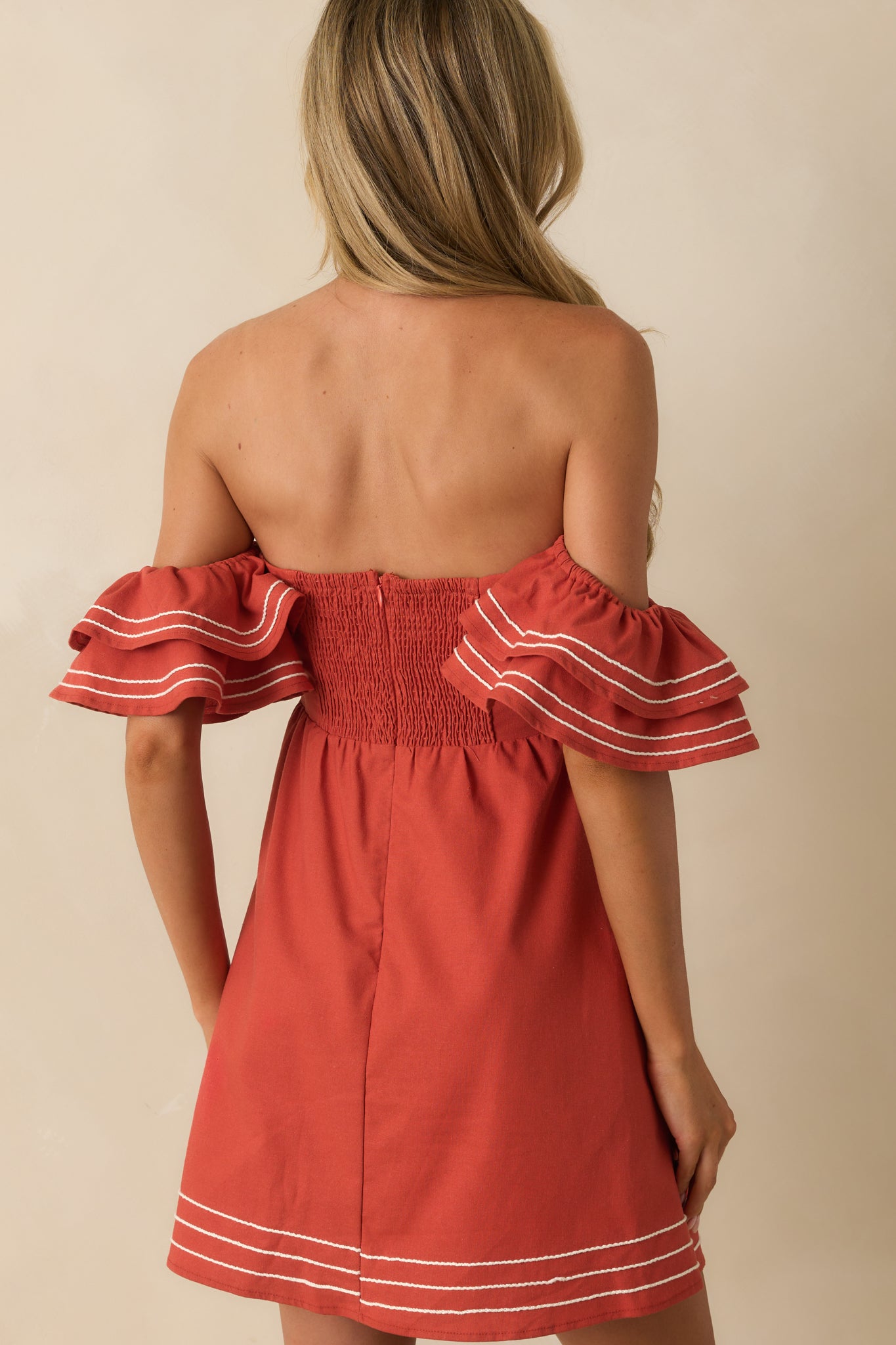 A back view of the dress showing the smocked panel, hidden zipper, and adjustable flutter sleeves.