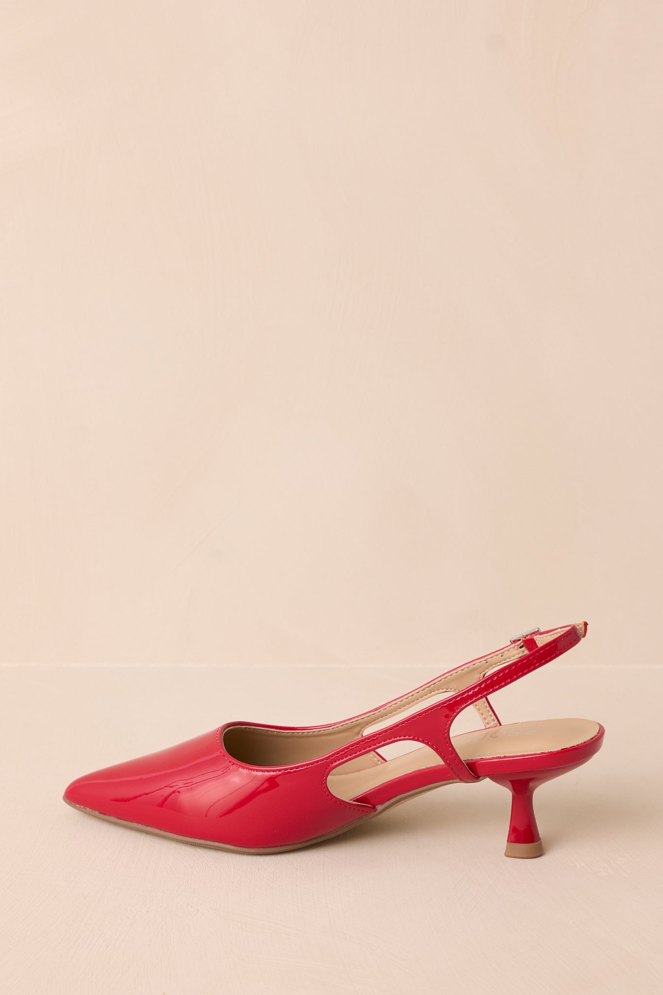 Back view showing the pointed heel, strap with gold buckle, and smooth red finish.