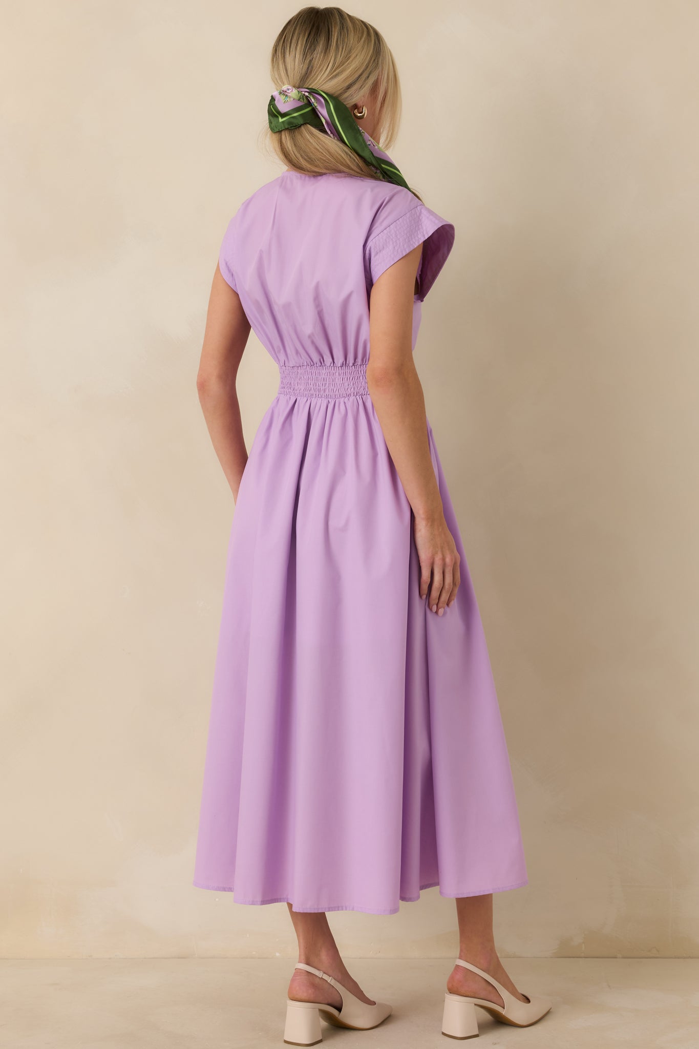 Back view of the lavender midi dress showing the sleeveless cut, tailored waist shaping, and softly gathered skirt at midi length.