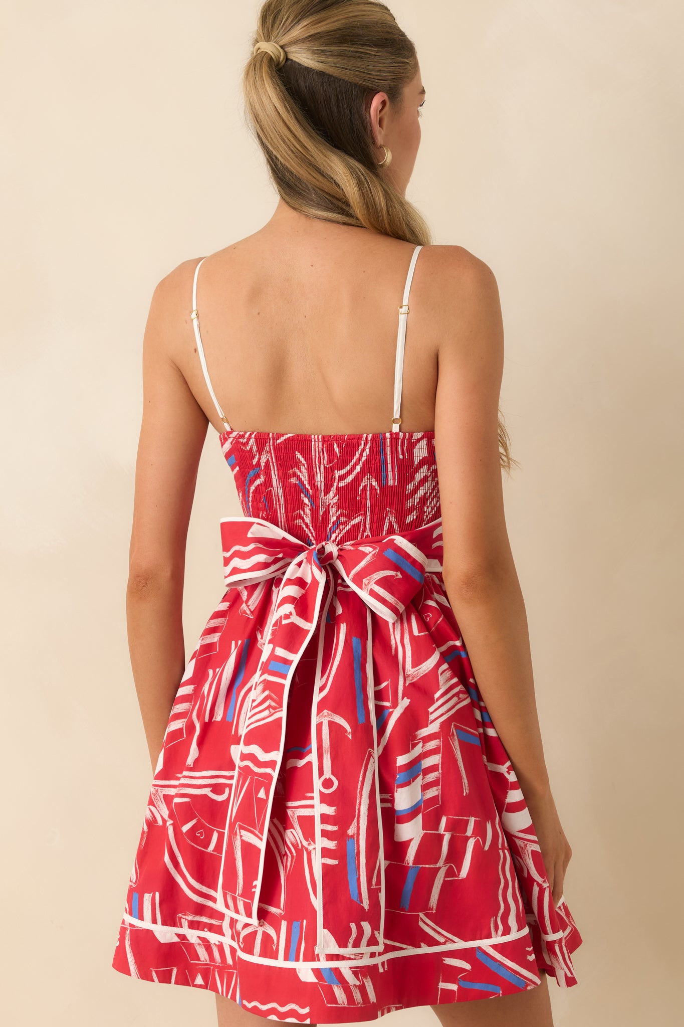 Back view of the cotton mini dress featuring adjustable straps, smocked back, and gathered skirt silhouette.