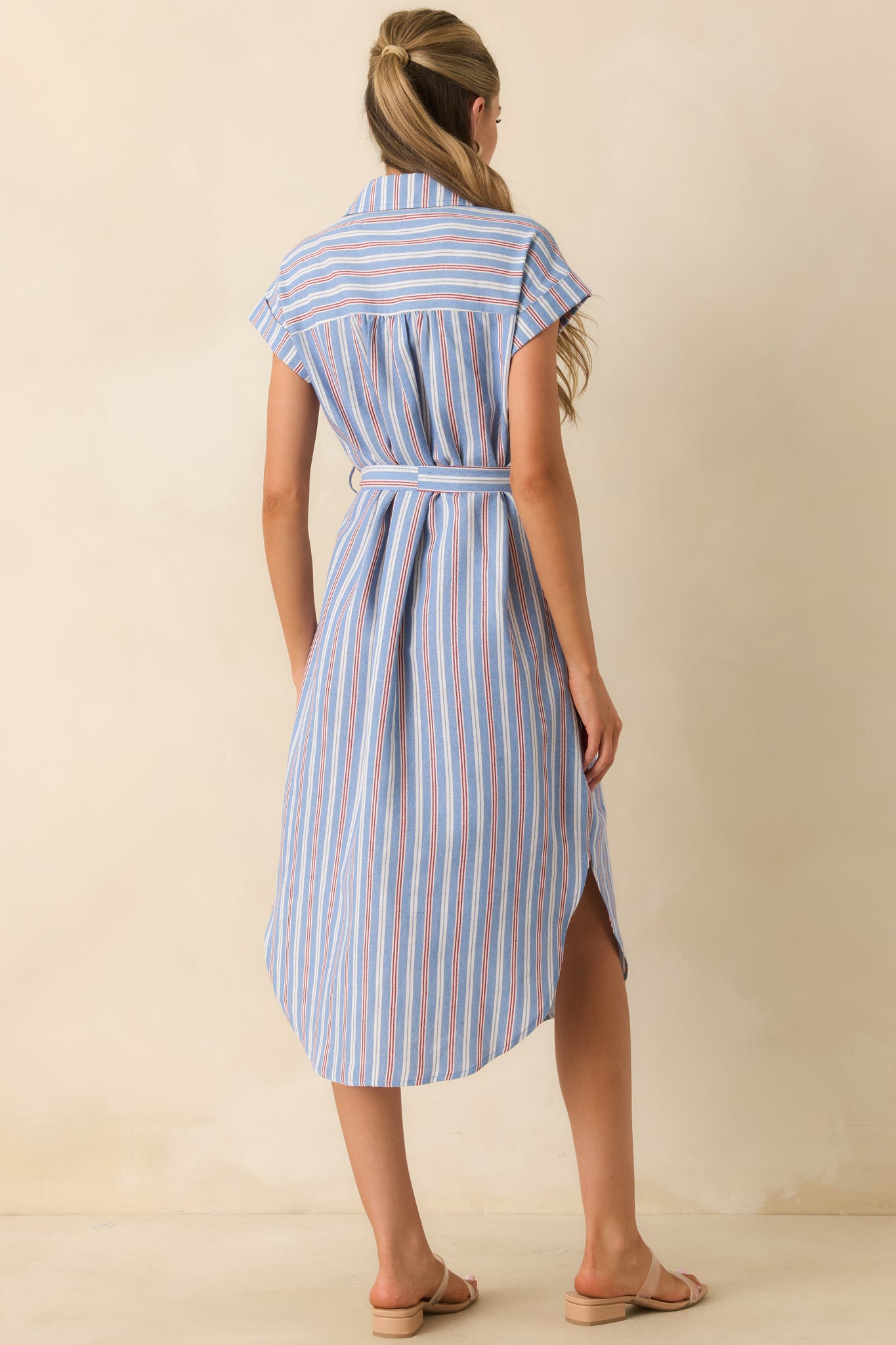 Back view of the blue, red, and ivory striped midi dress featuring cap sleeves, a self-tie belt, and a flowing curved hem.