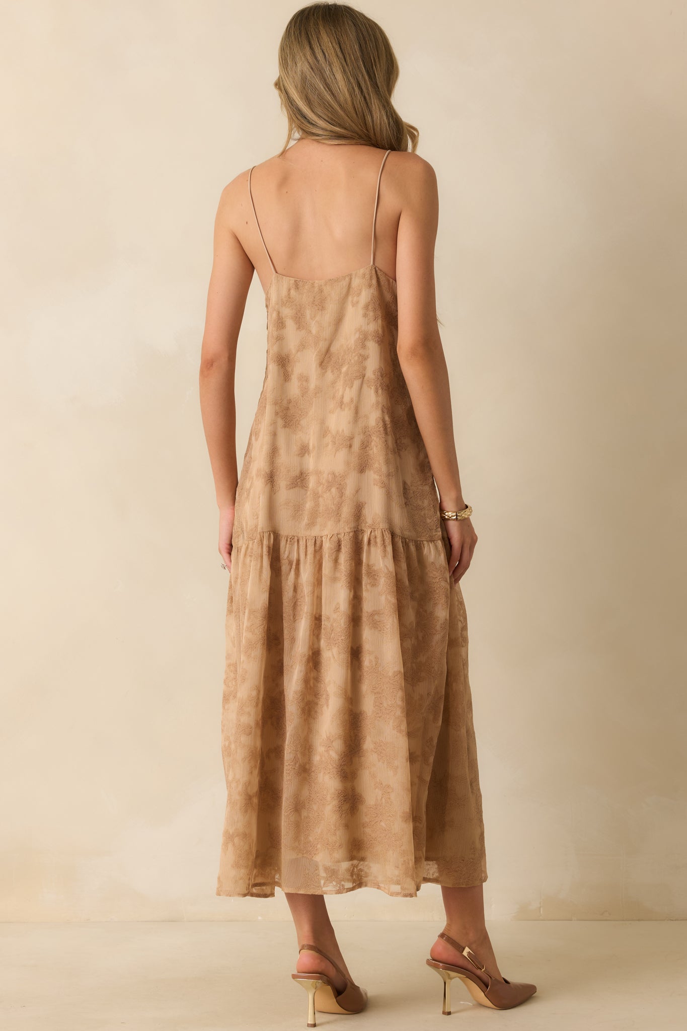 A back view of the tan maxi dress featuring a concealed side zipper, straight neckline, and flowing tiered skirt.