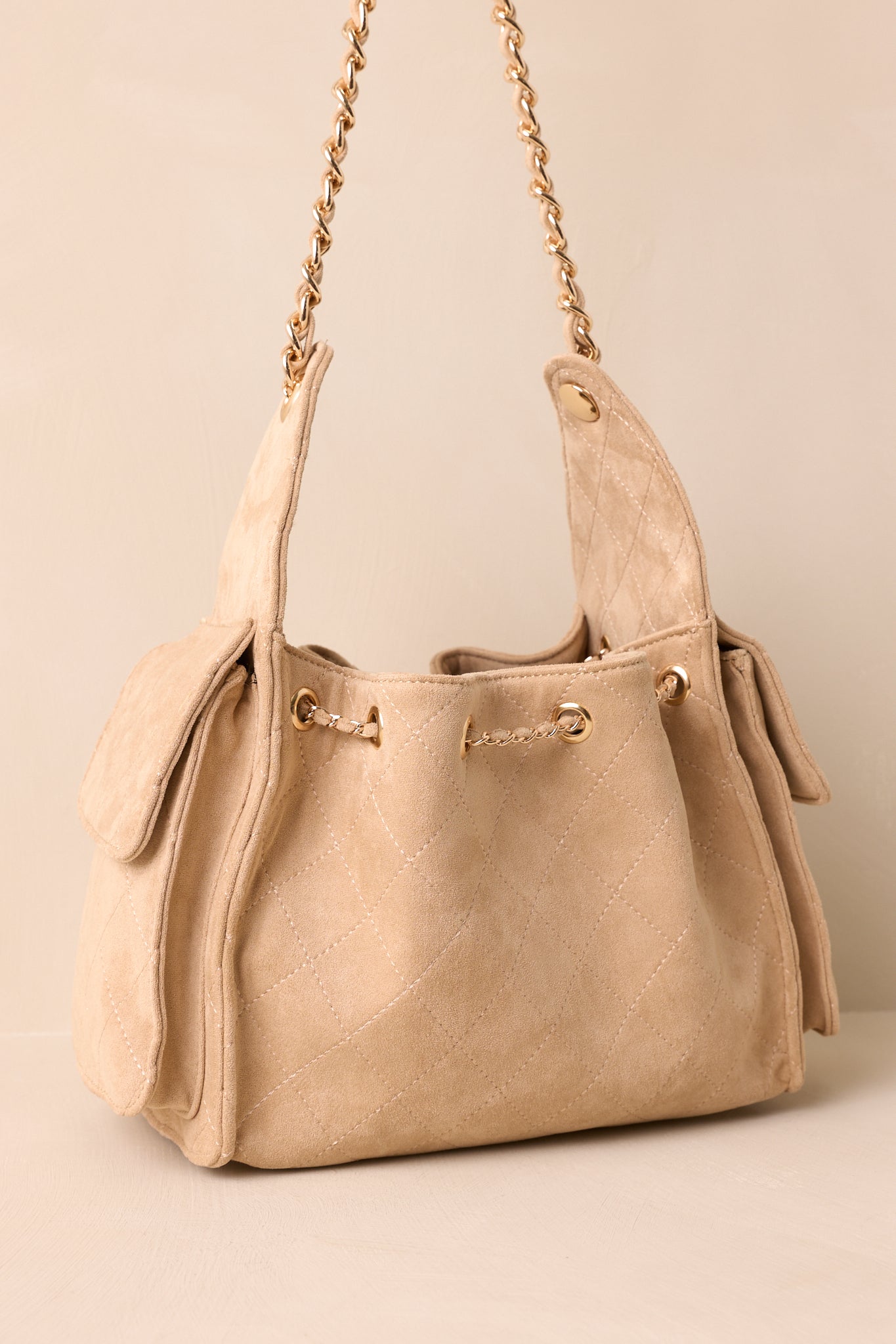 Back view of taupe quilted purse showing smooth faux leather surface and detachable strap attachment.