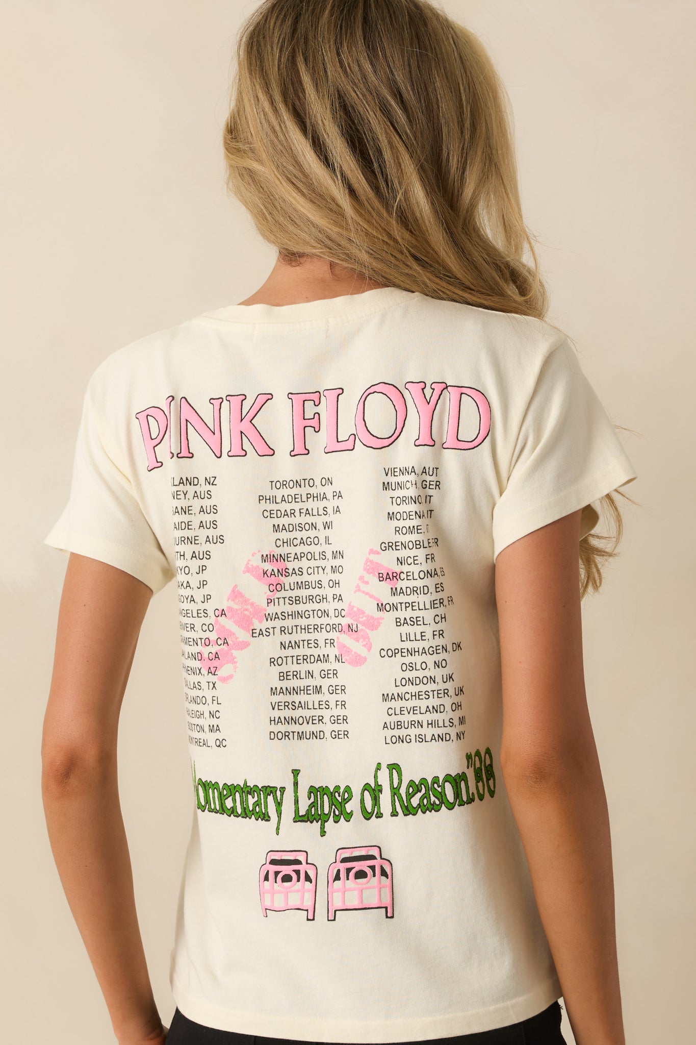 A back view of the tee featuring a pink "Pink Floyd" graphic with a list of cities written in black.