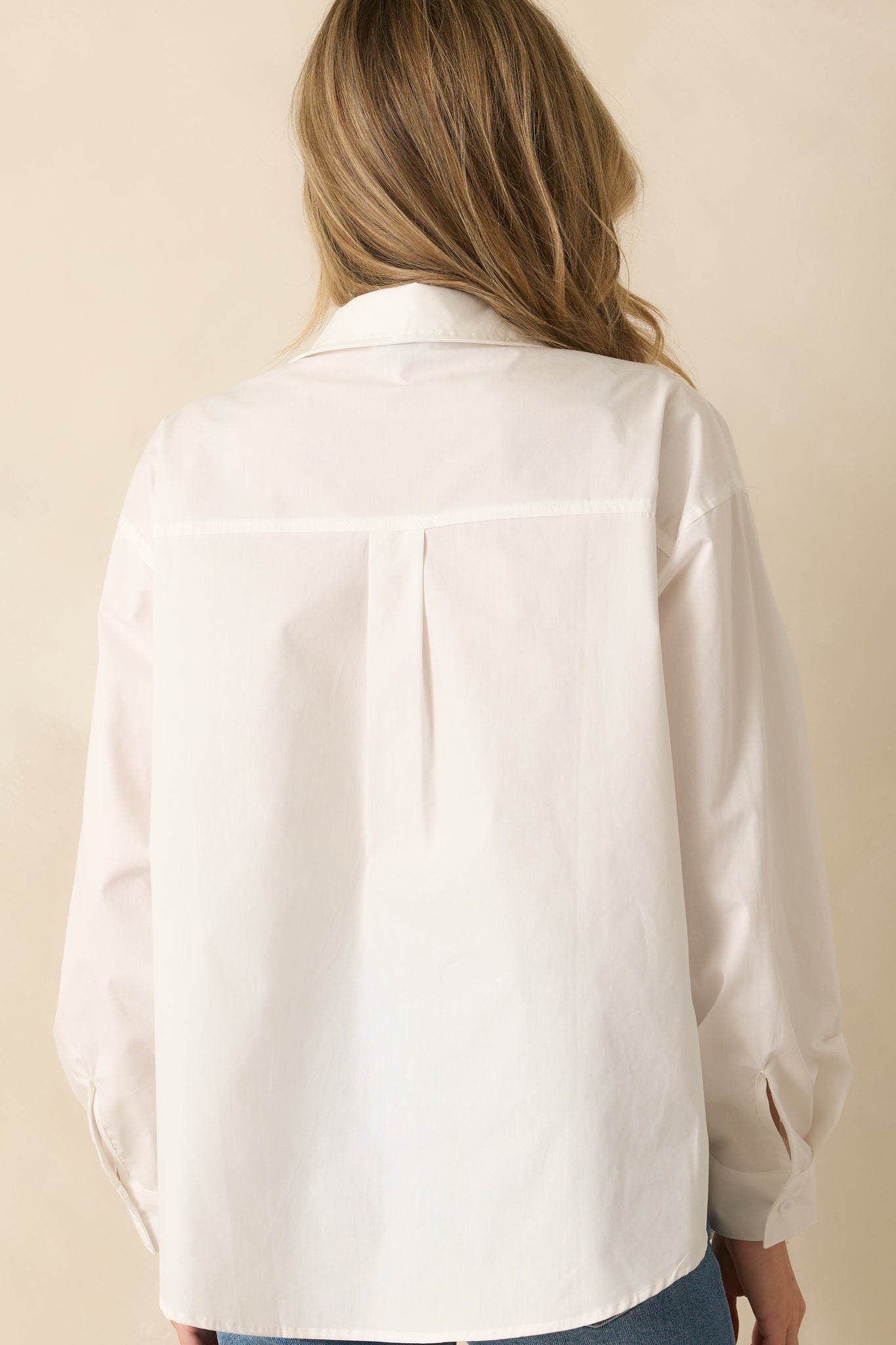 A back view of the white top displaying the relaxed fit and straight back design.
