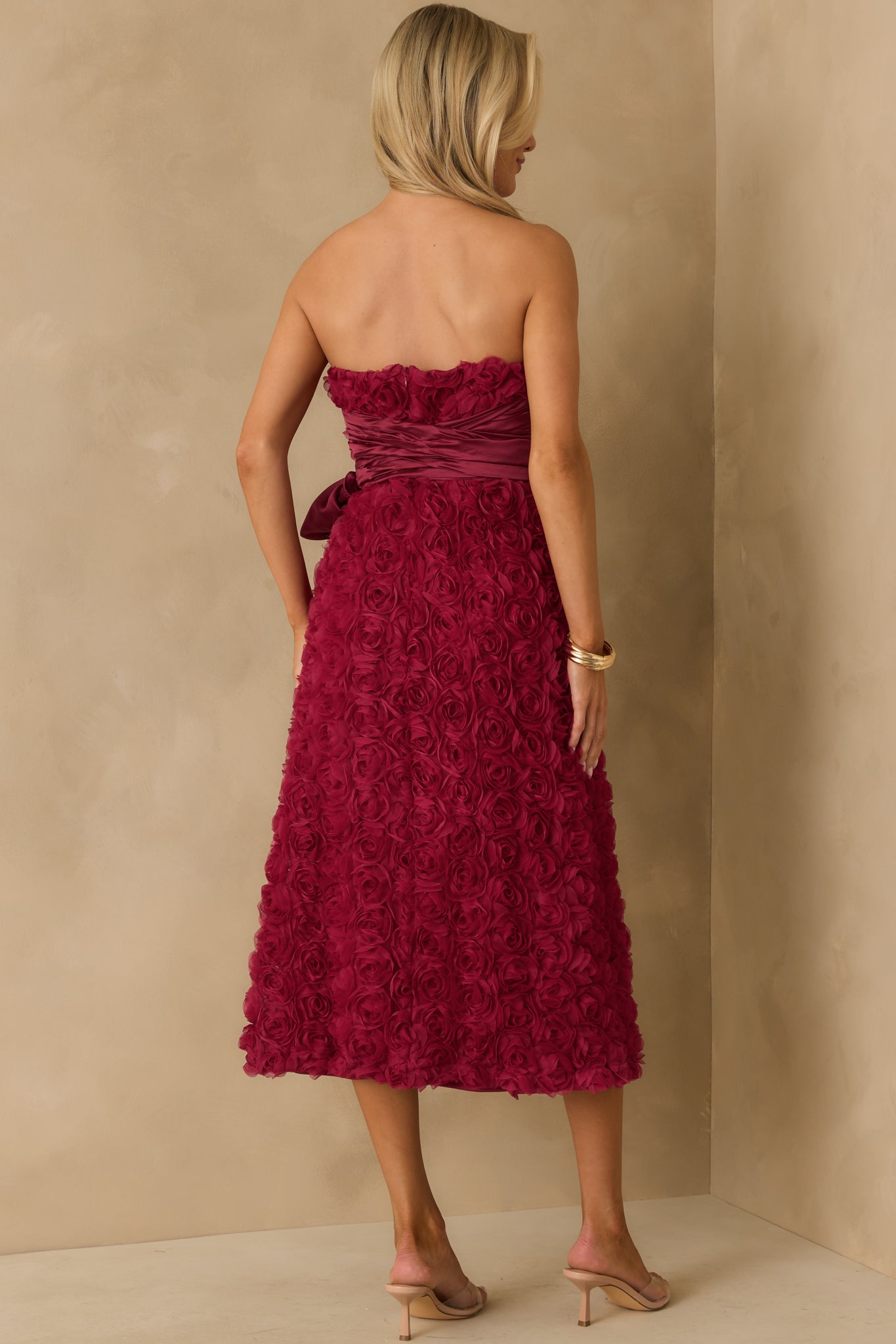 A back view of the wine strapless dress highlighting the discrete back zipper and bow tie detail.